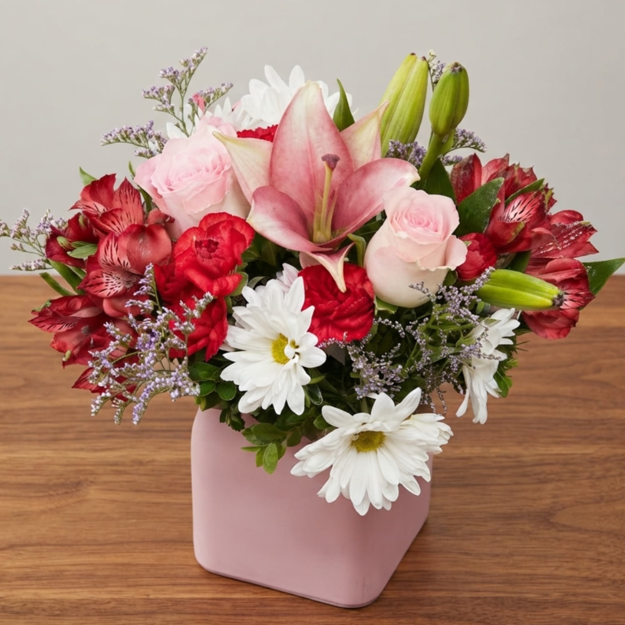 Pink and red mixed bouquet in a pink vase with white daisies
