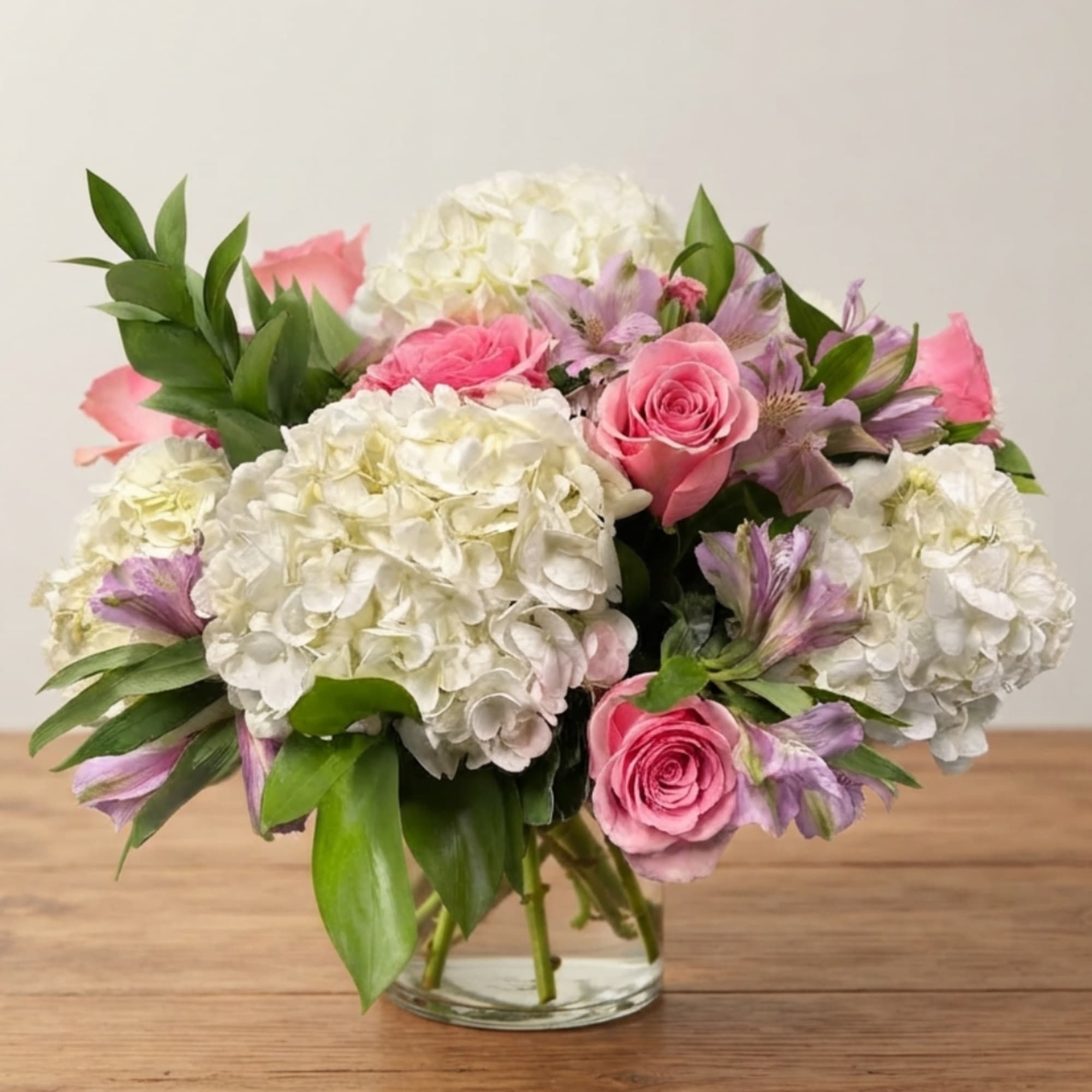 Pink roses and white hydrangeas in a clear glass vase