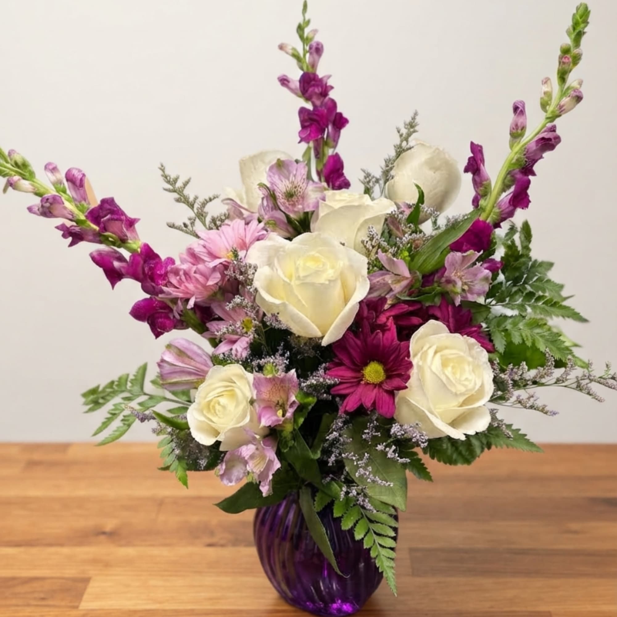 Purple and white mixed bouquet in a purple glass vase