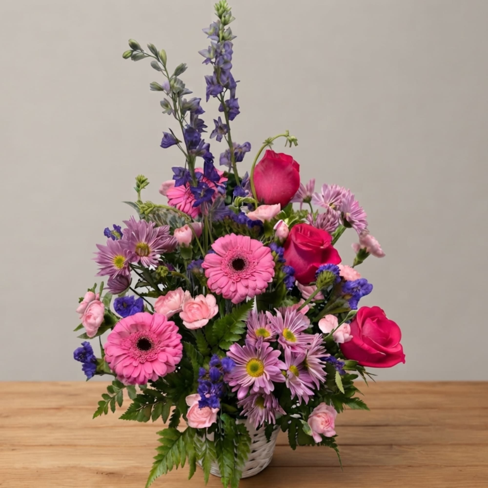 Pink and purple mixed flower arrangement in a white basket