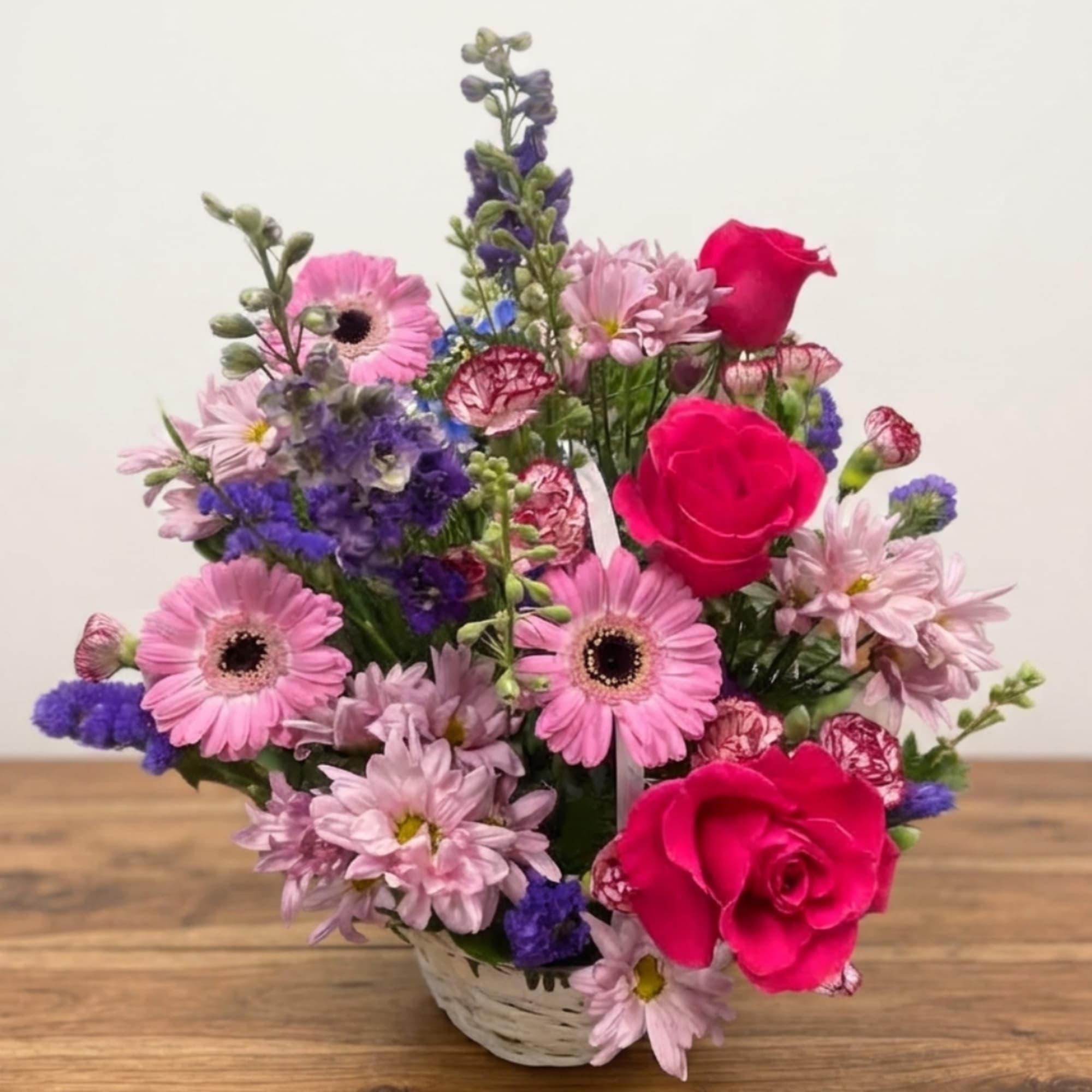 Pink and purple mixed flower arrangement in a white basket, photo 2 of 4