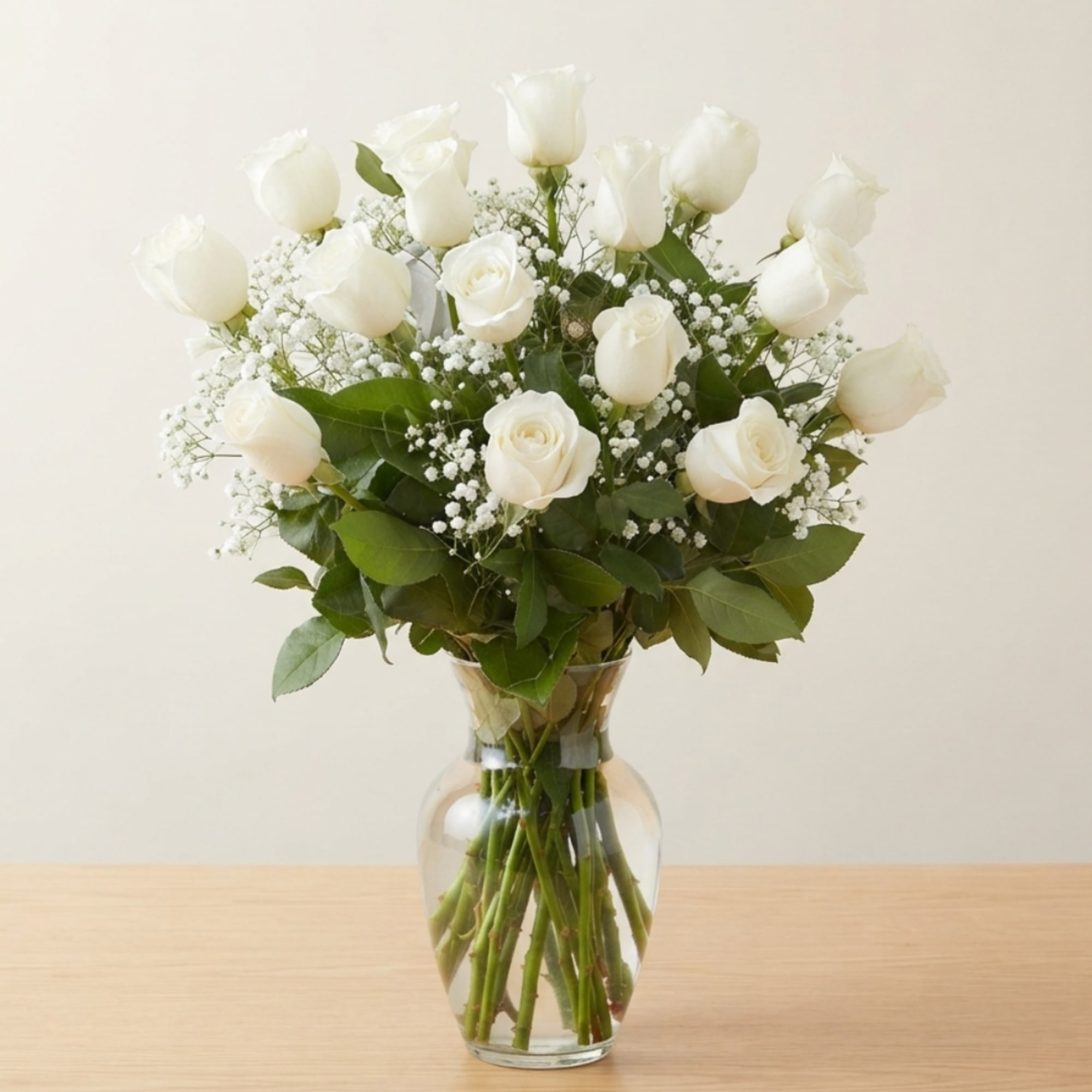 White roses arranged in a clear glass vase with baby's breath