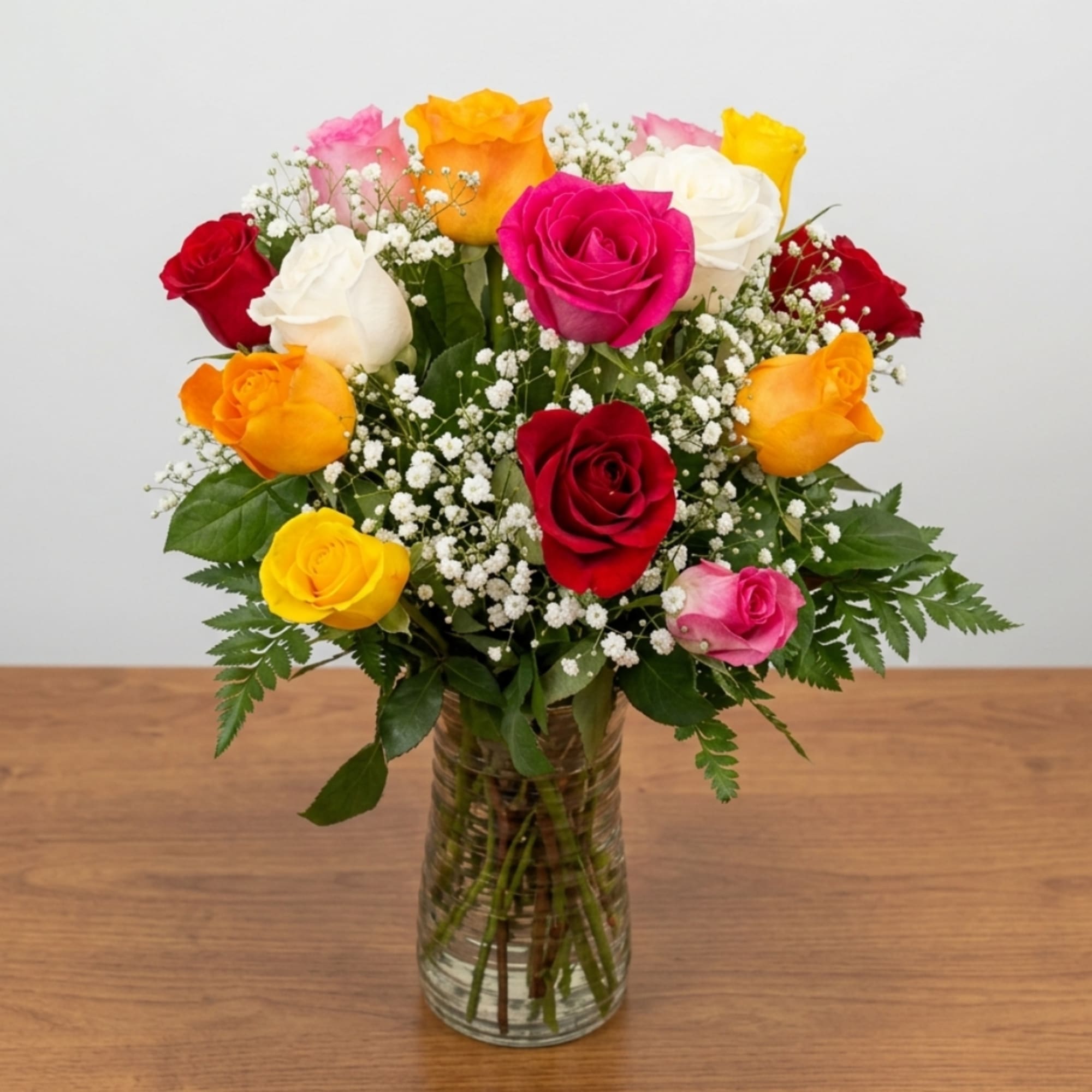 Mixed roses in a clear glass vase with baby's breath