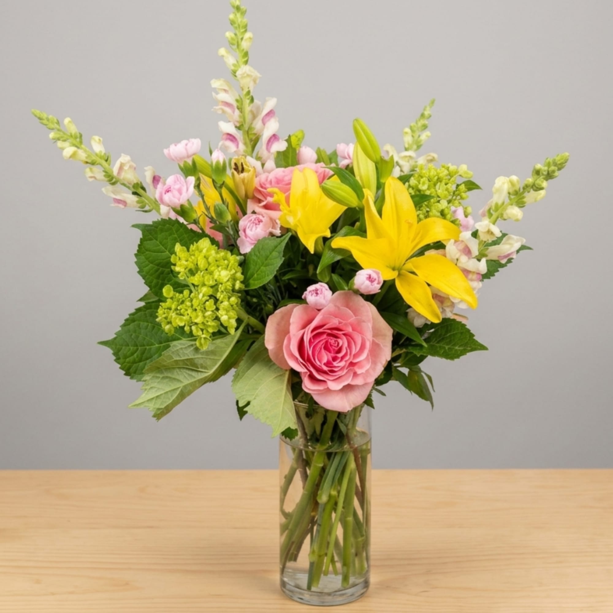Pink roses and yellow lilies in a clear glass vase