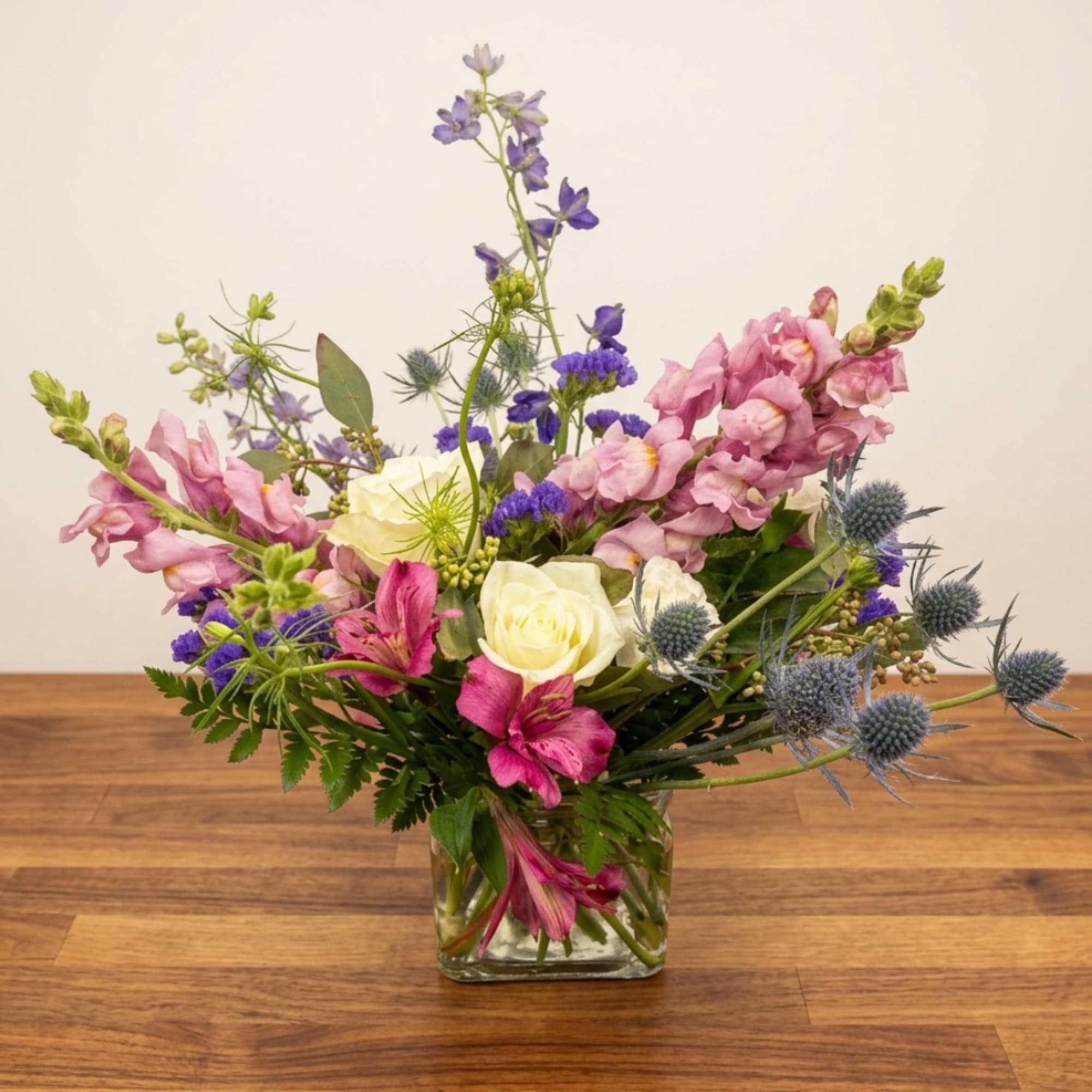 Mixed bouquet of pink, white, and purple flowers in a glass vase
