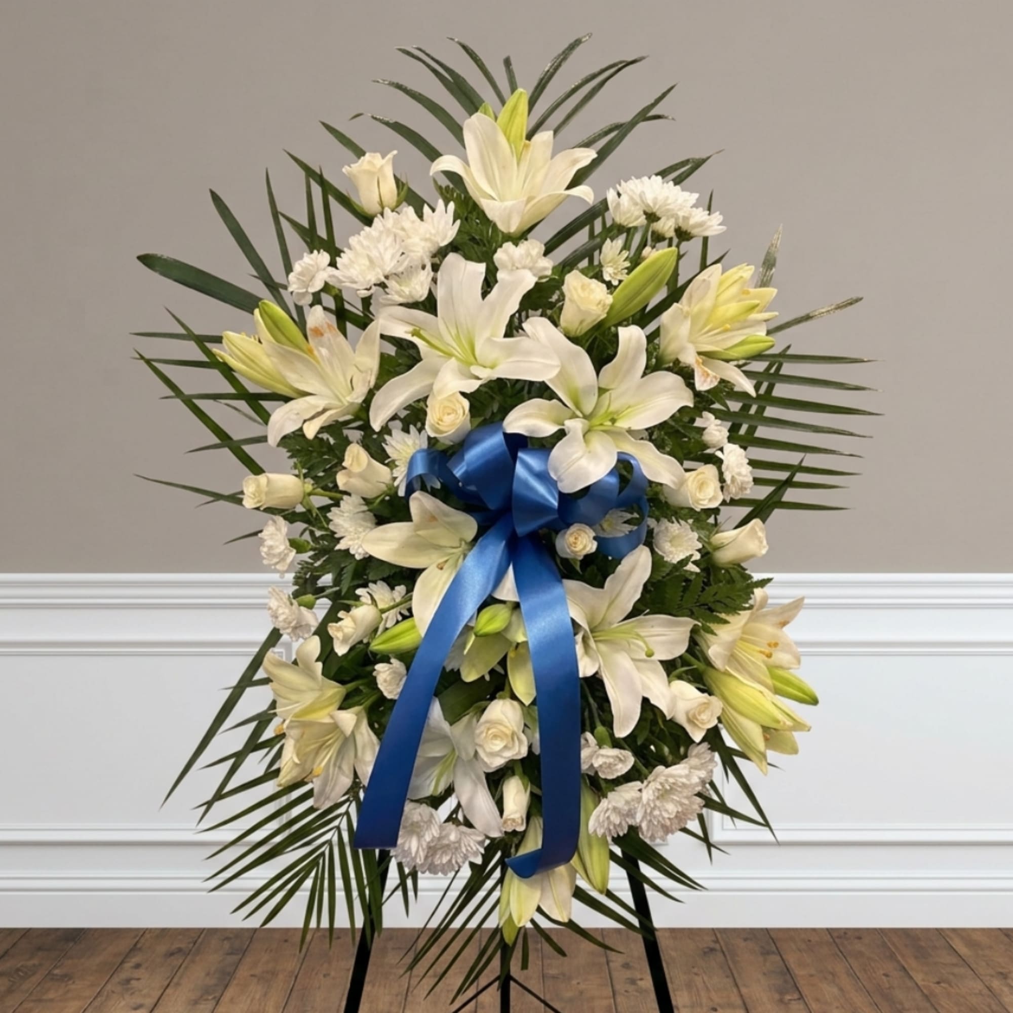 White lily and rose standing spray with a blue ribbon on an easel
