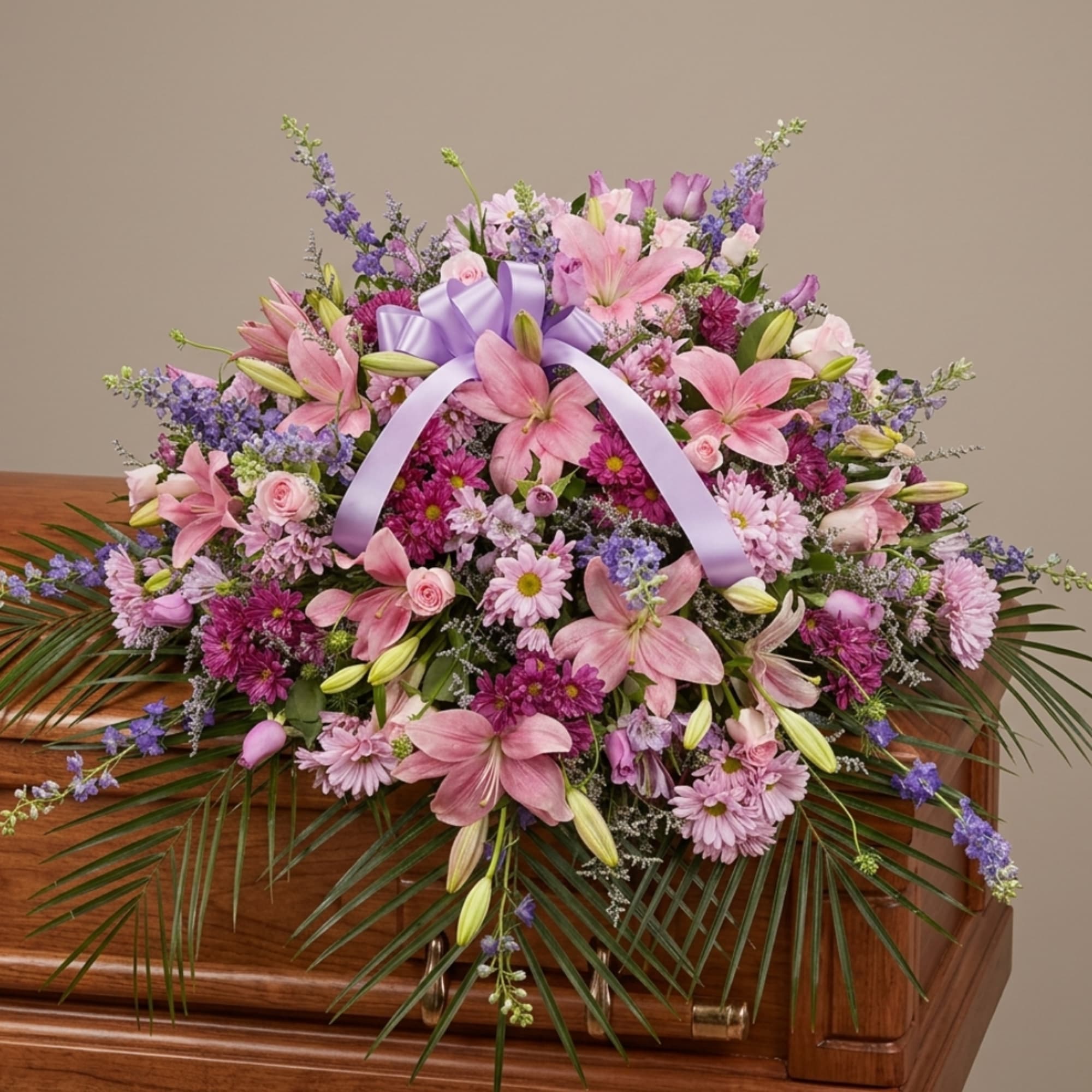 Pink and purple floral casket spray with a lavender ribbon