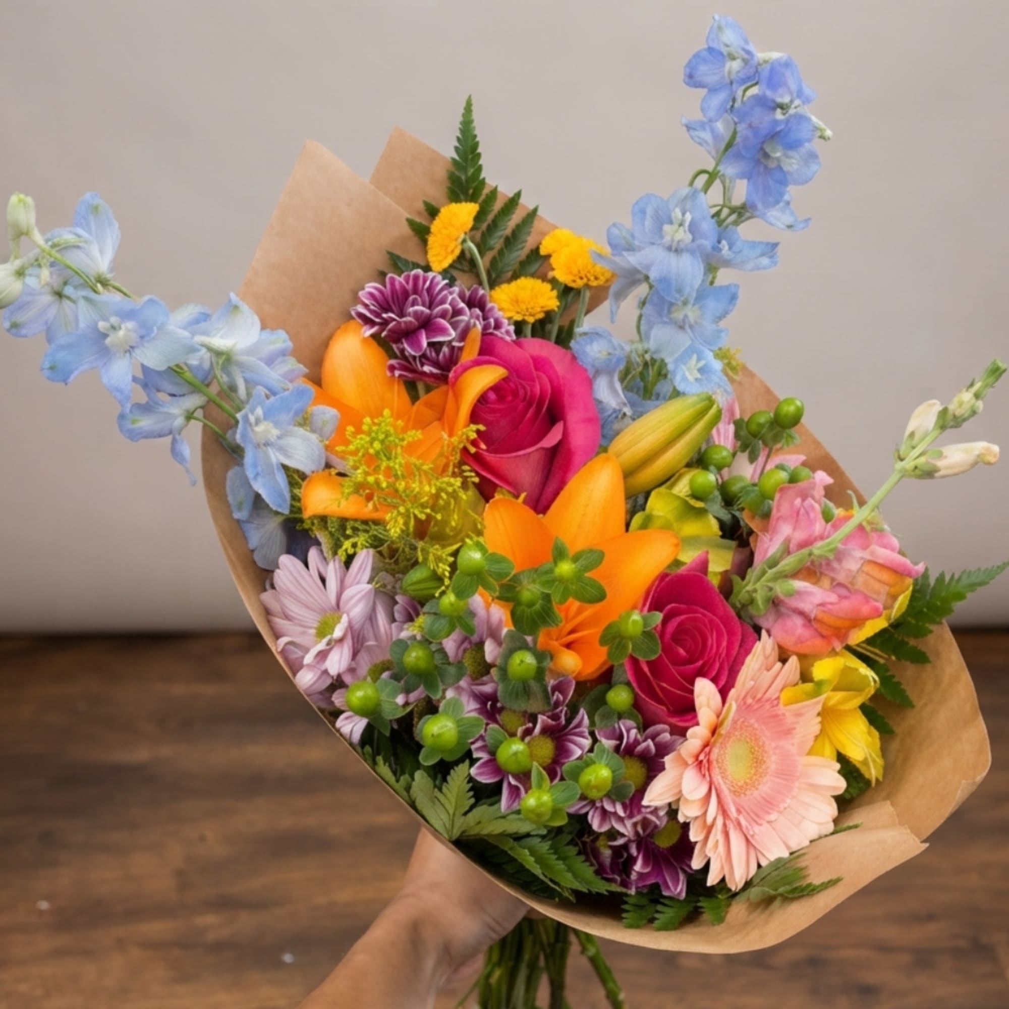 Colorful mixed bouquet with lilies, roses, daisies, and blue delphinium