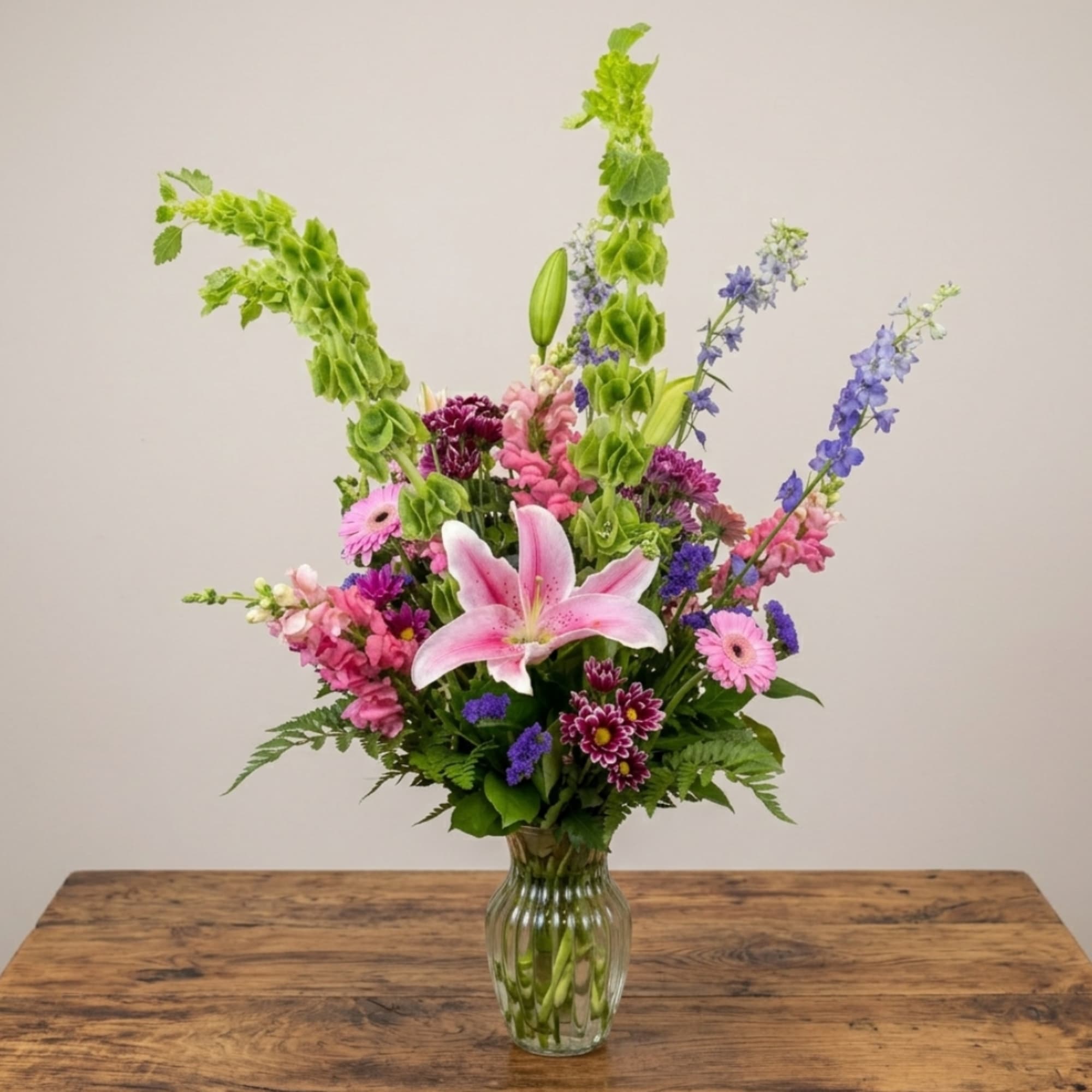Pink lily bouquet with purple and pink flowers in a glass vase
