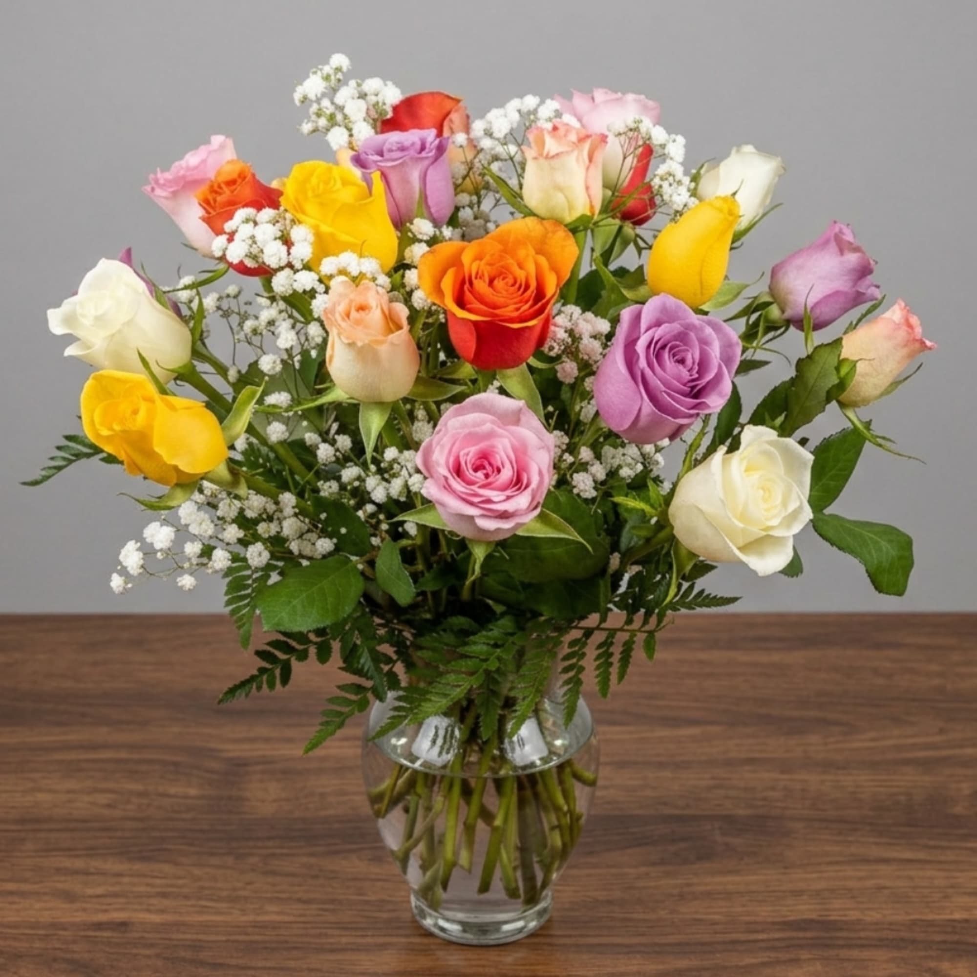 Mixed roses in a clear glass vase with white filler flowers