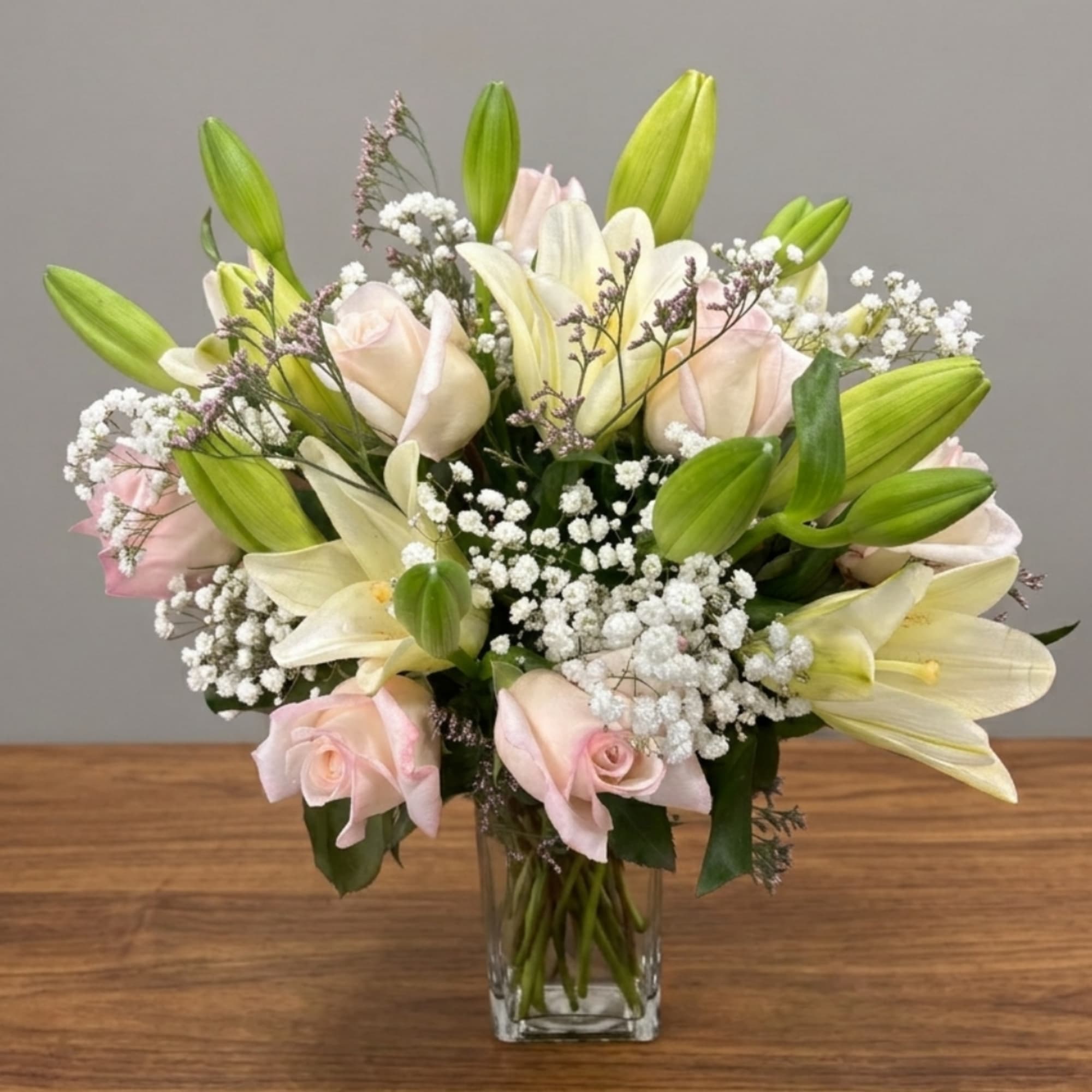 Bouquet of pale pink roses and white lilies in a clear glass vase