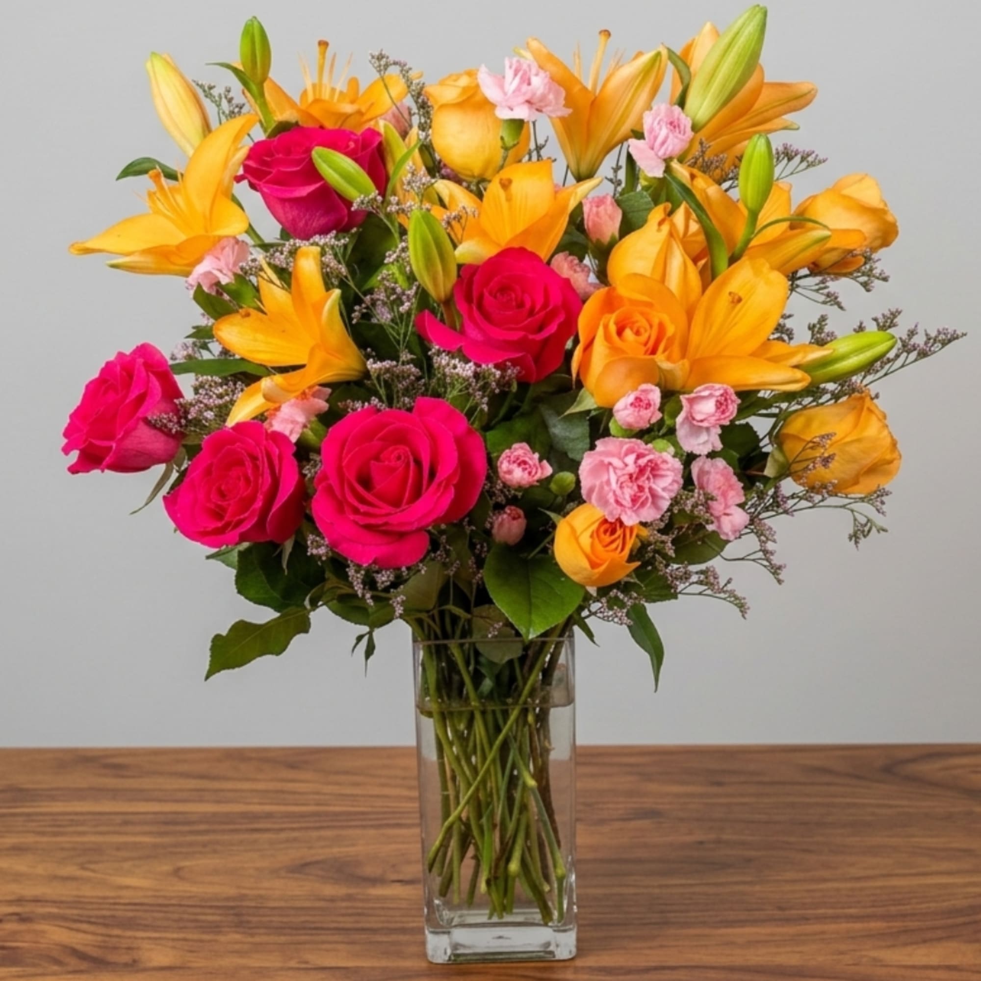 Bright mixed bouquet of roses and lilies in a clear glass vase
