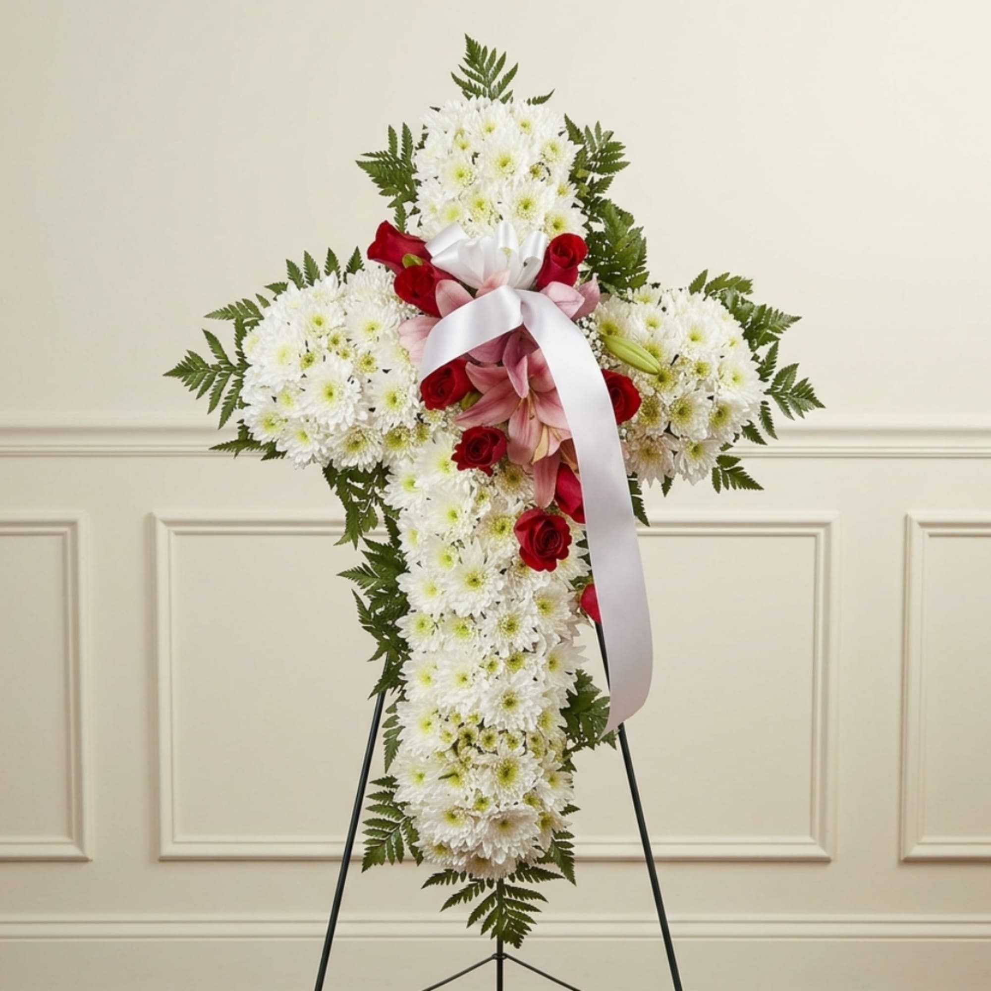 White chrysanthemum cross with red roses and pink lilies on a stand
