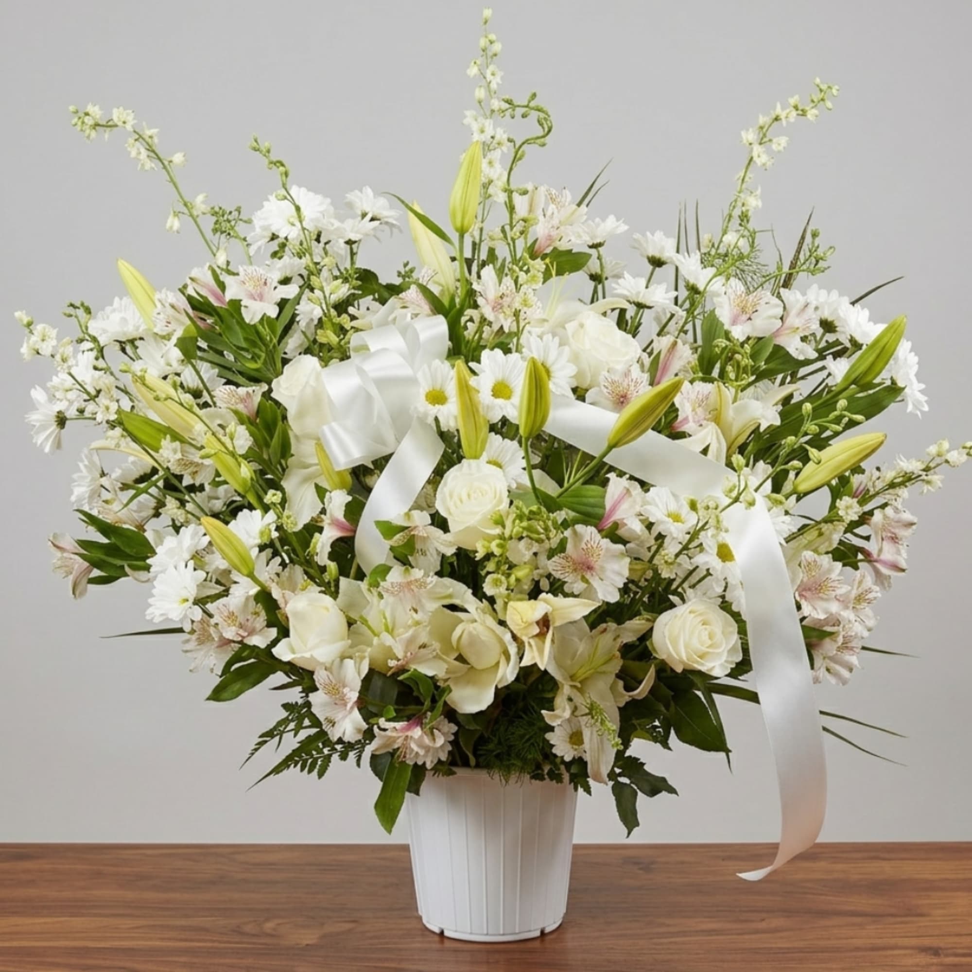 White floral arrangement in a white vase with a satin ribbon