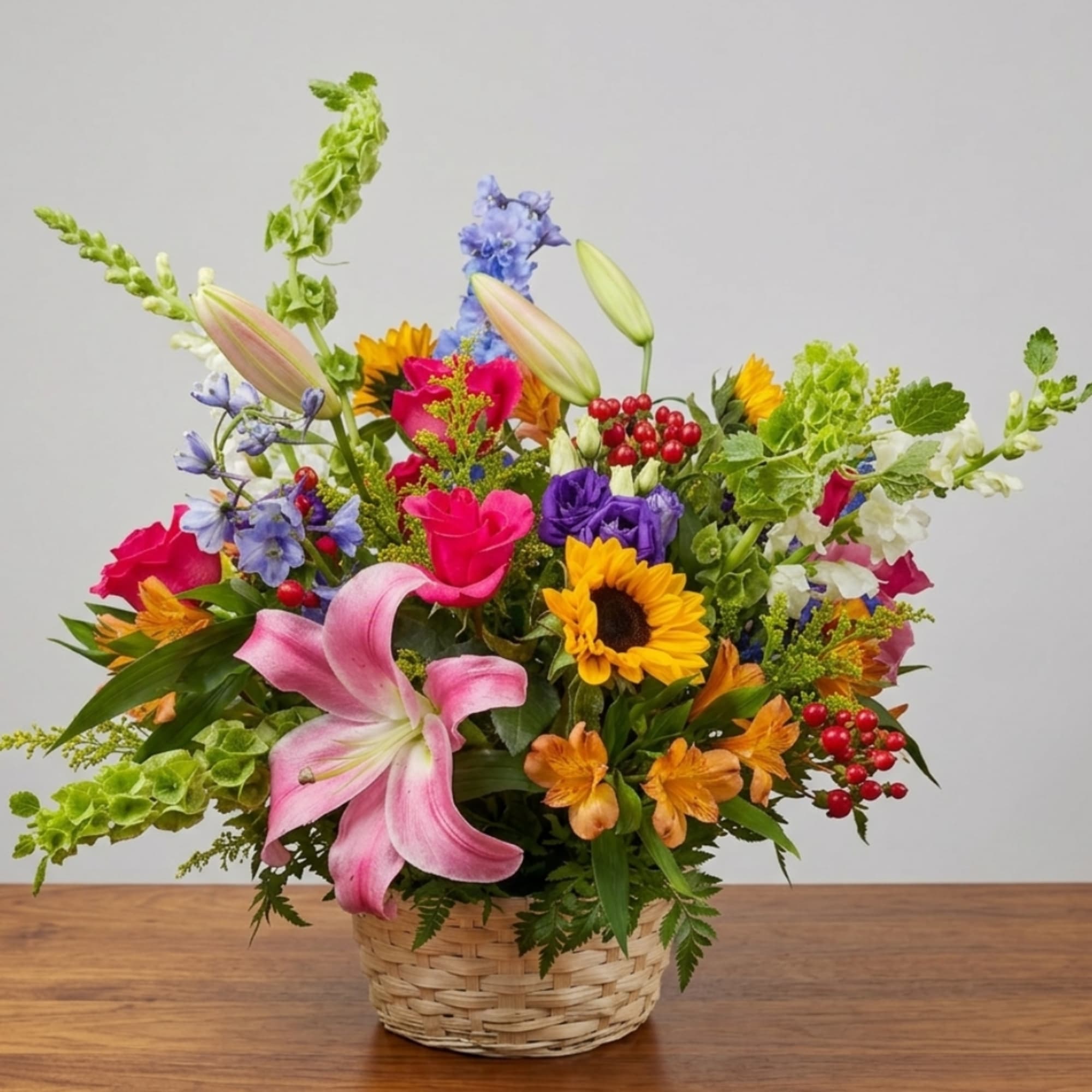 Mixed bouquet in a woven basket with lilies, sunflowers, and colorful blooms