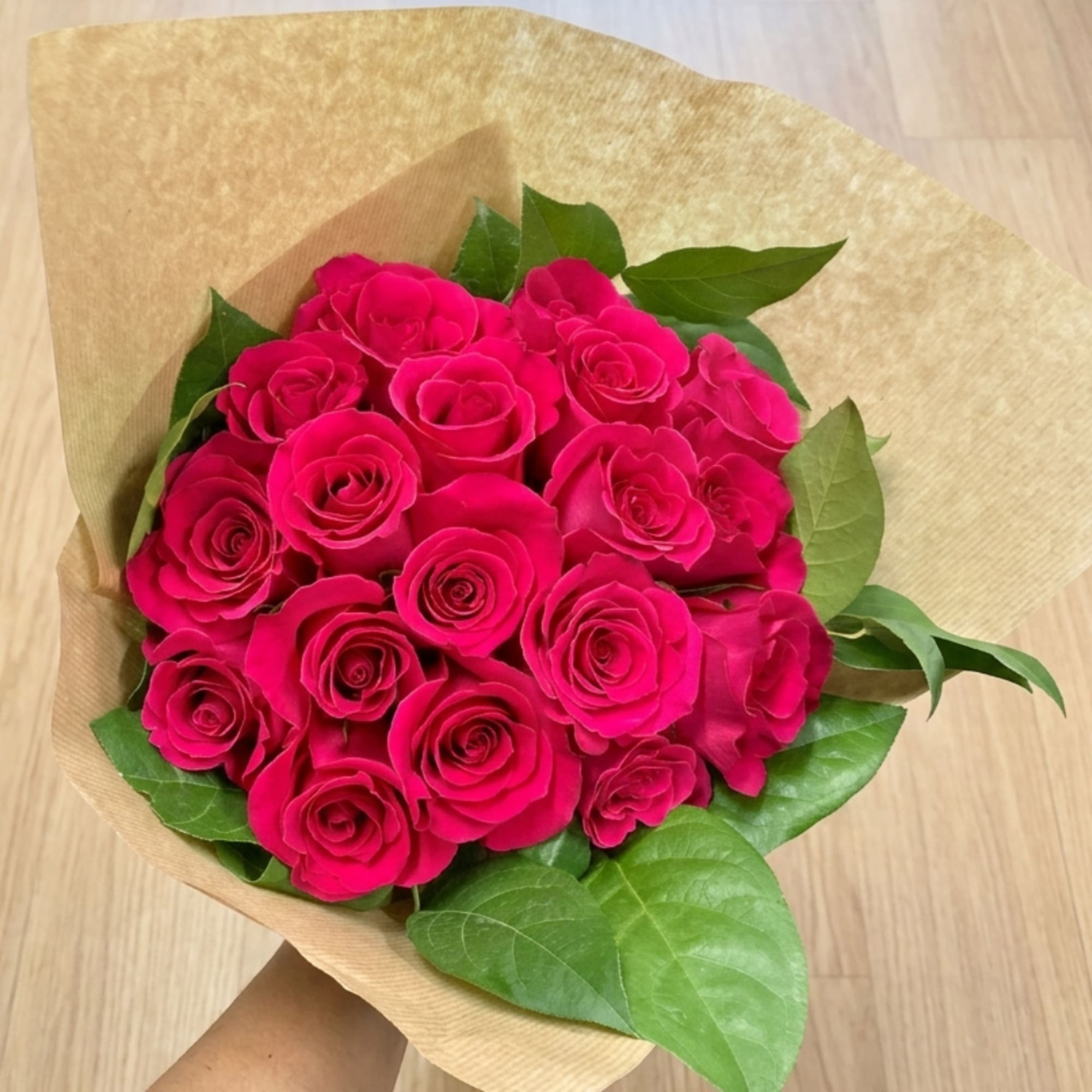 Bouquet of bright pink roses wrapped in brown paper