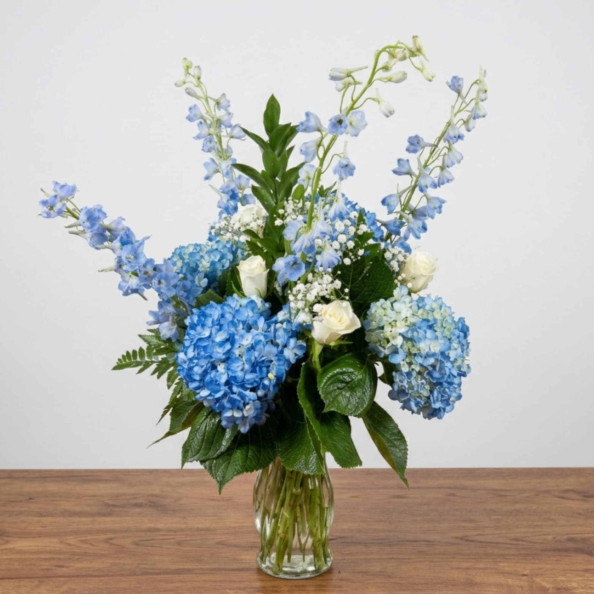 Blue hydrangeas and white roses in a clear glass vase