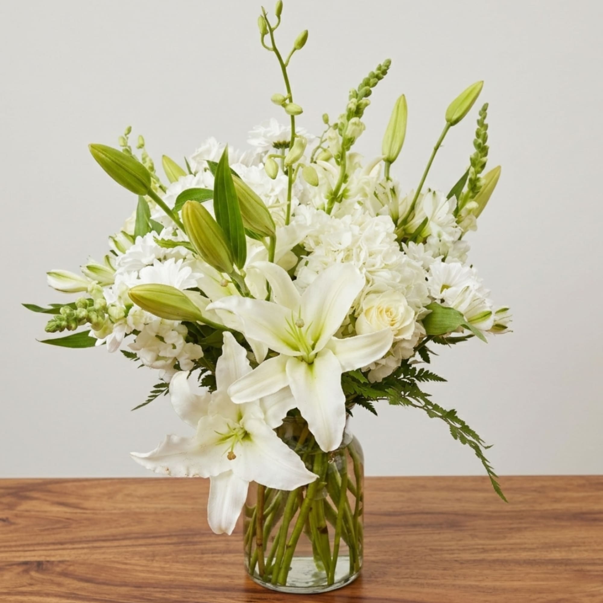 White lilies and roses in a clear glass vase