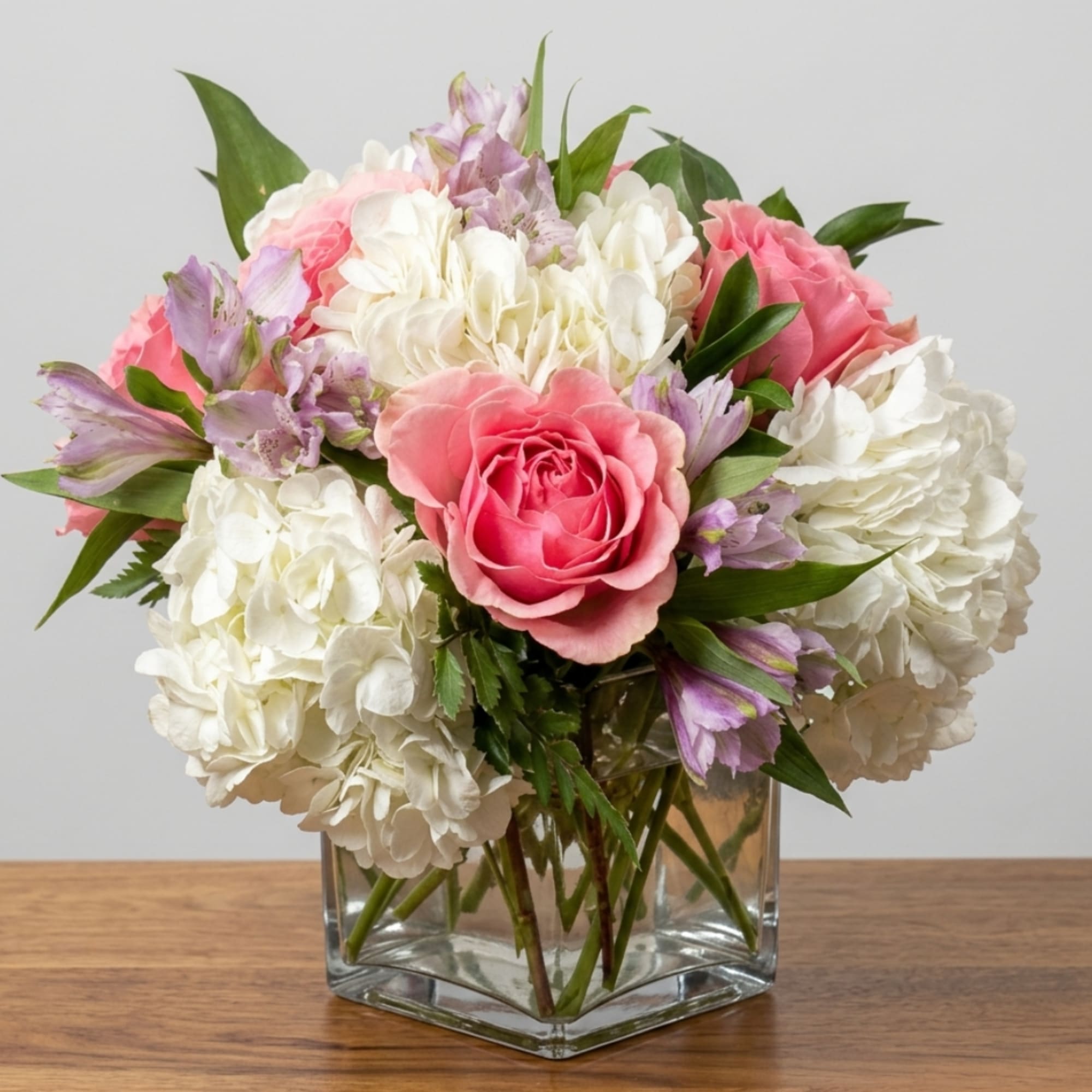 Pink roses and white hydrangeas in a clear glass vase