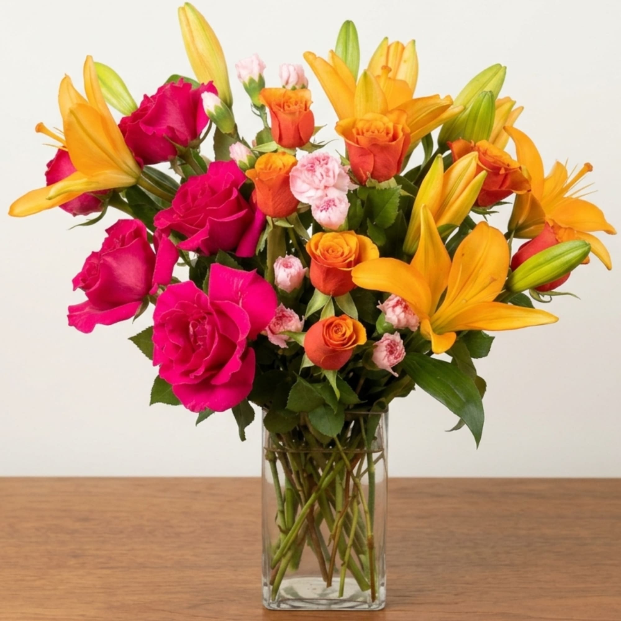 Bouquet of pink roses and orange lilies in a clear glass vase