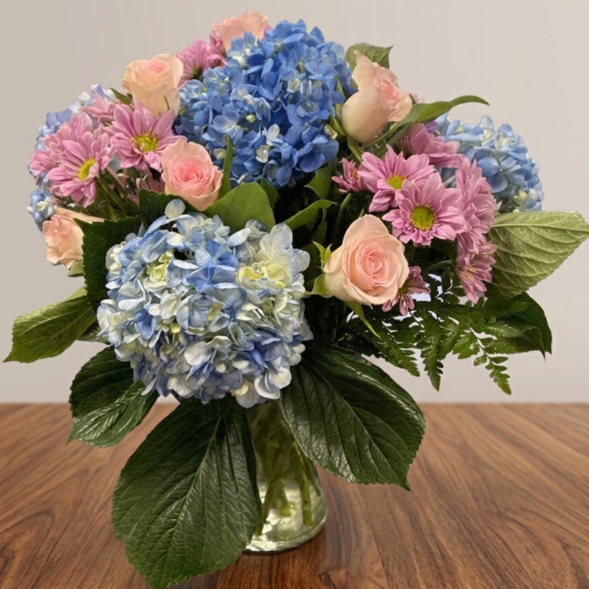 Pink roses and blue hydrangeas in a glass vase