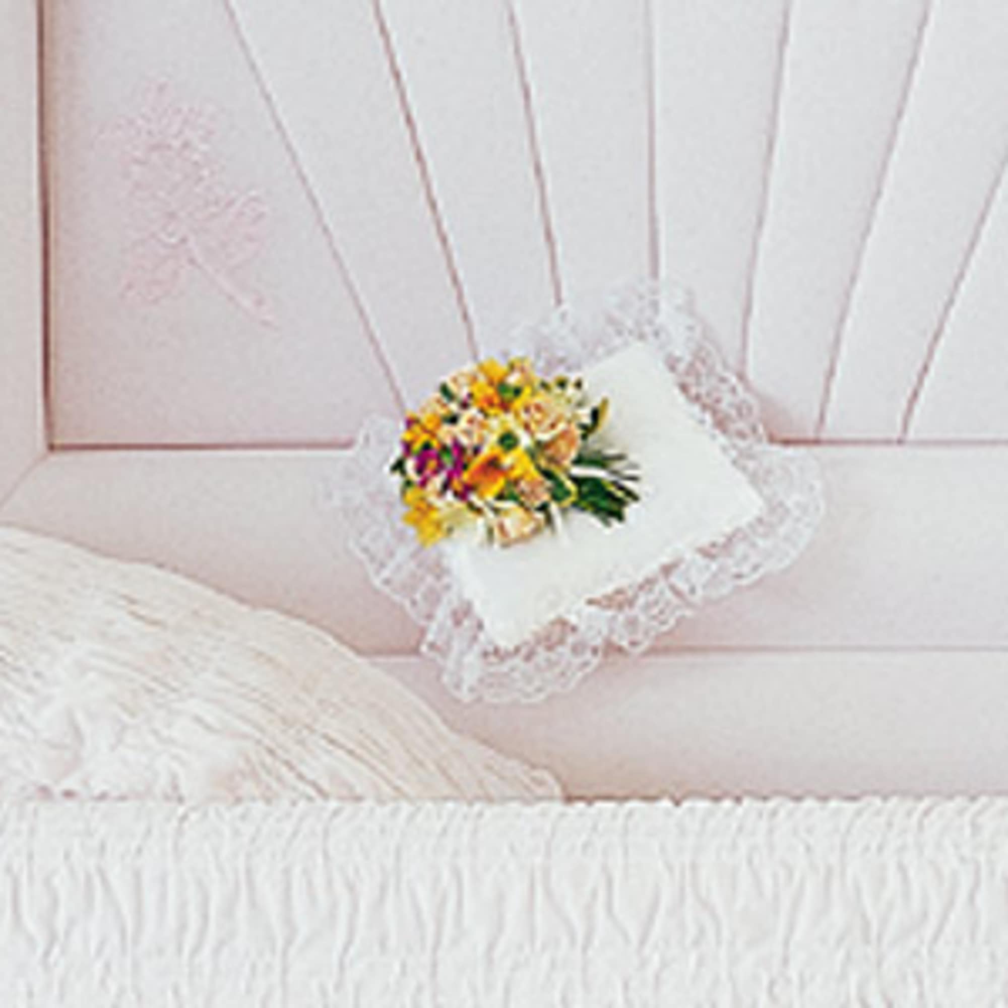 Small floral pillow with lace trim on a pink bedspread