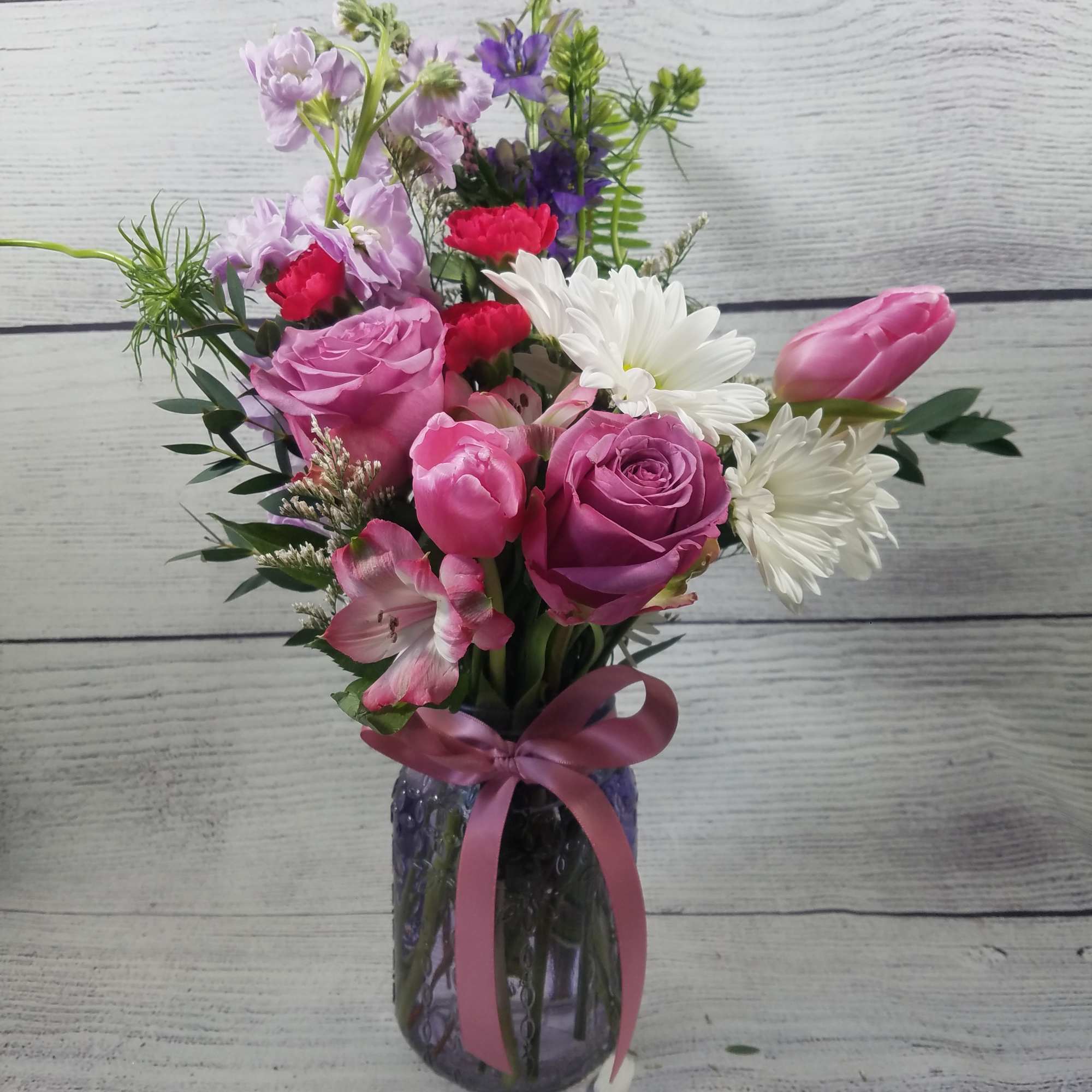 Pink and white mixed bouquet in a glass vase with a ribbon