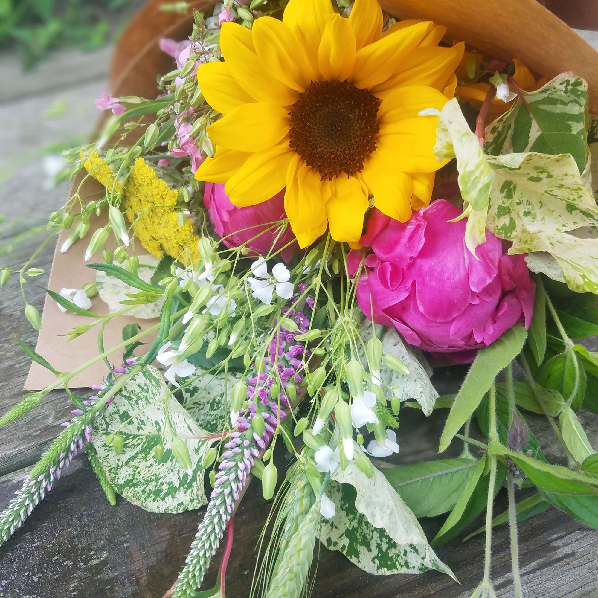 Bouquet with a yellow sunflower and pink blooms wrapped in brown paper