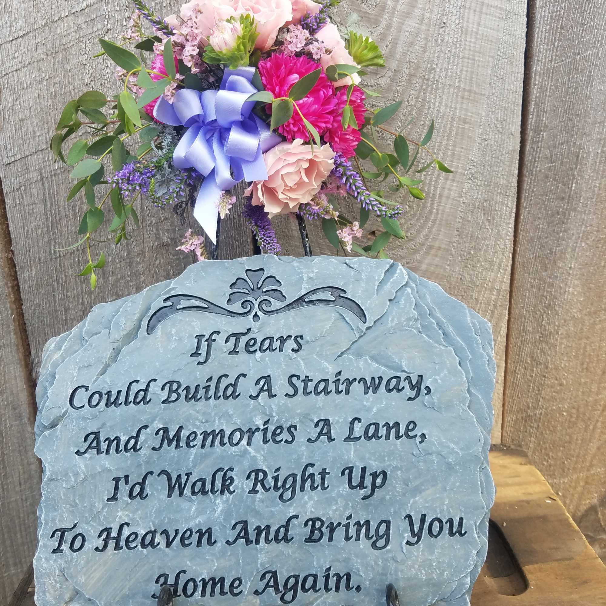 Pink and purple floral tribute on a memorial stone plaque