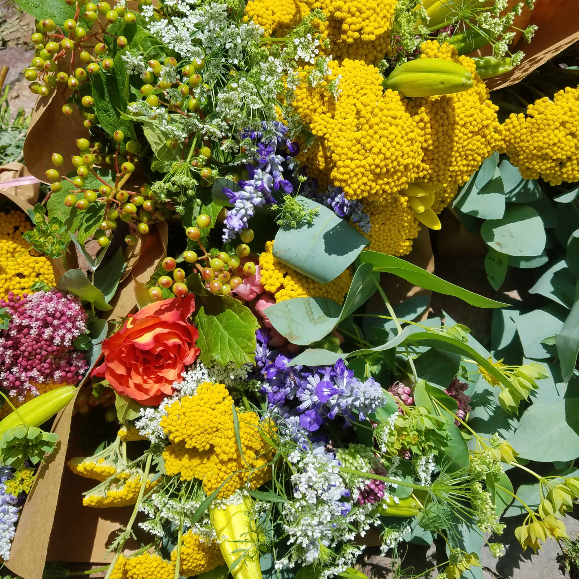 Mixed bouquet with yellow blooms, red roses, and purple flowers