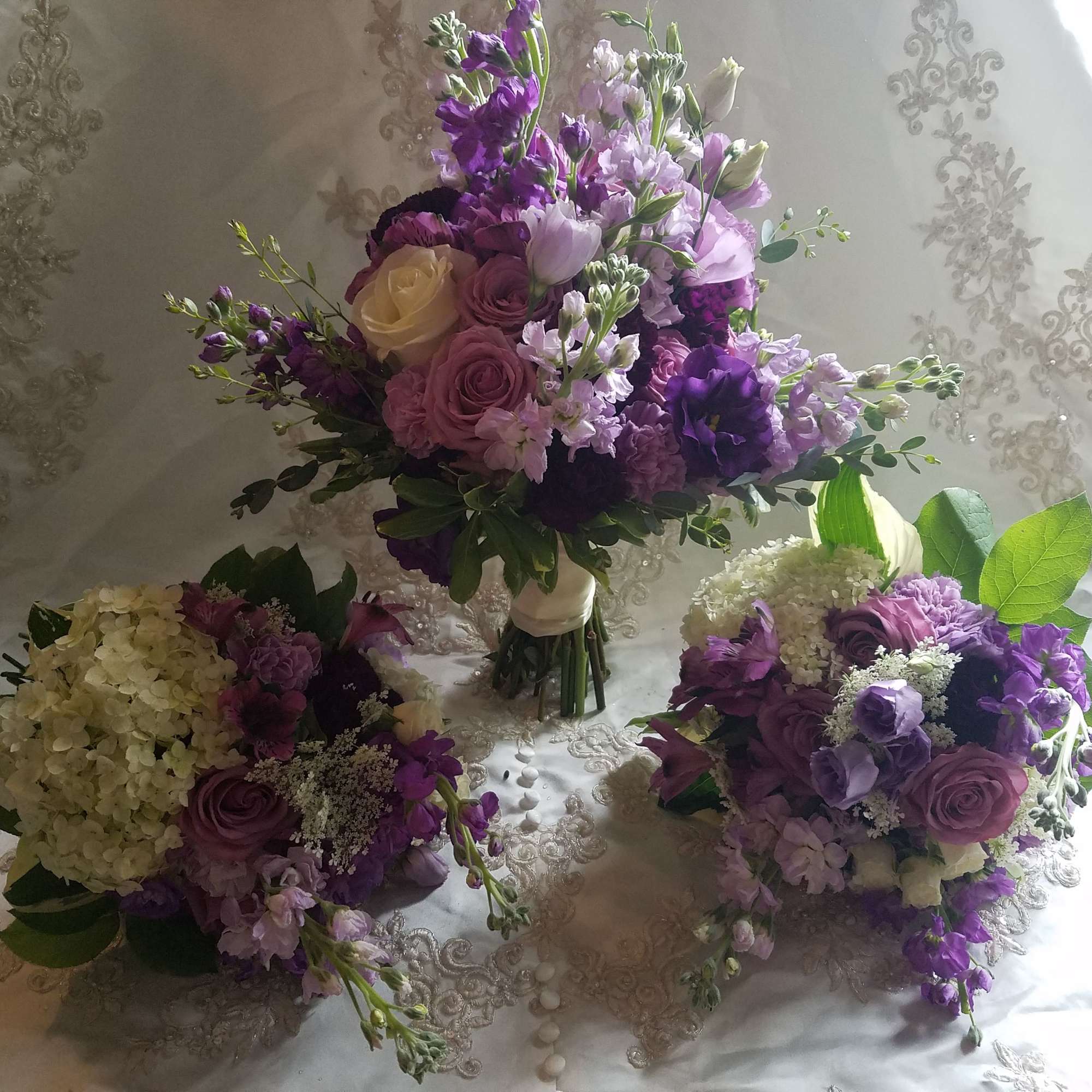 Three purple and white floral bouquets on a patterned white cloth