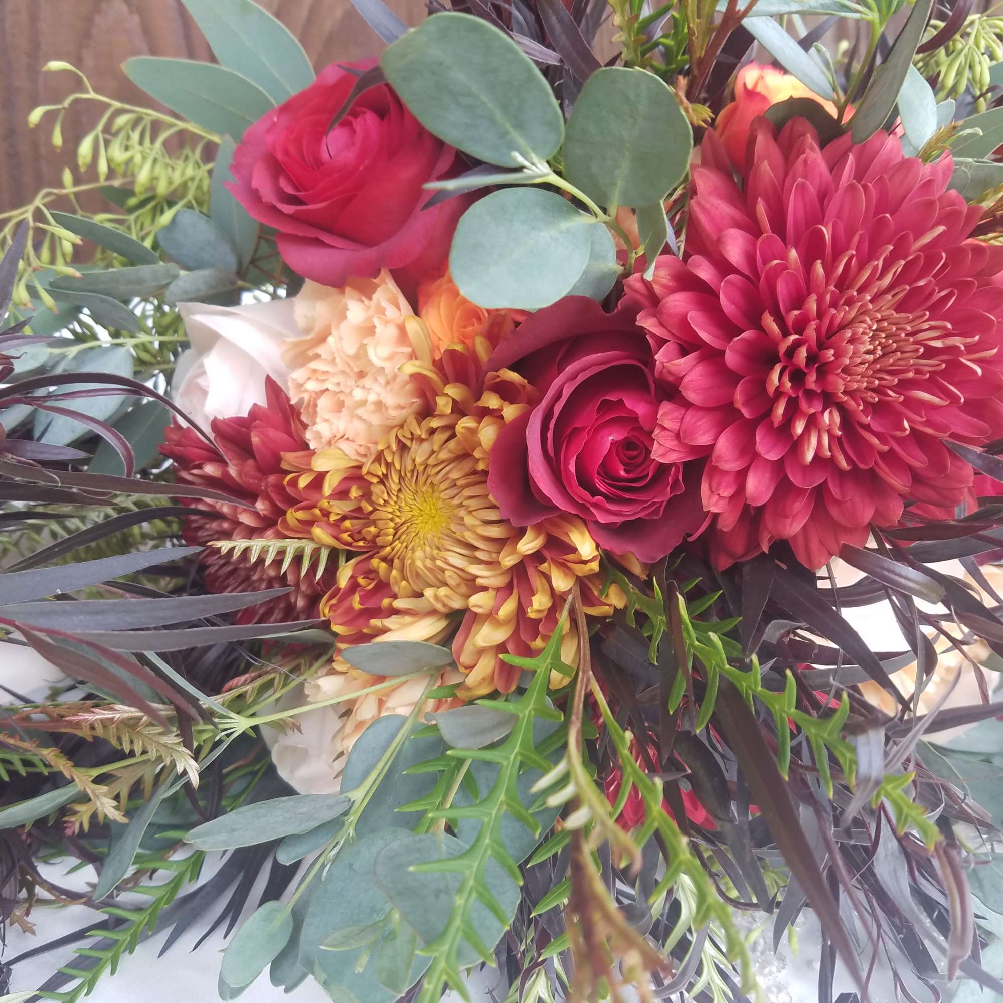 Bouquet of burgundy and peach flowers with eucalyptus and dark foliage