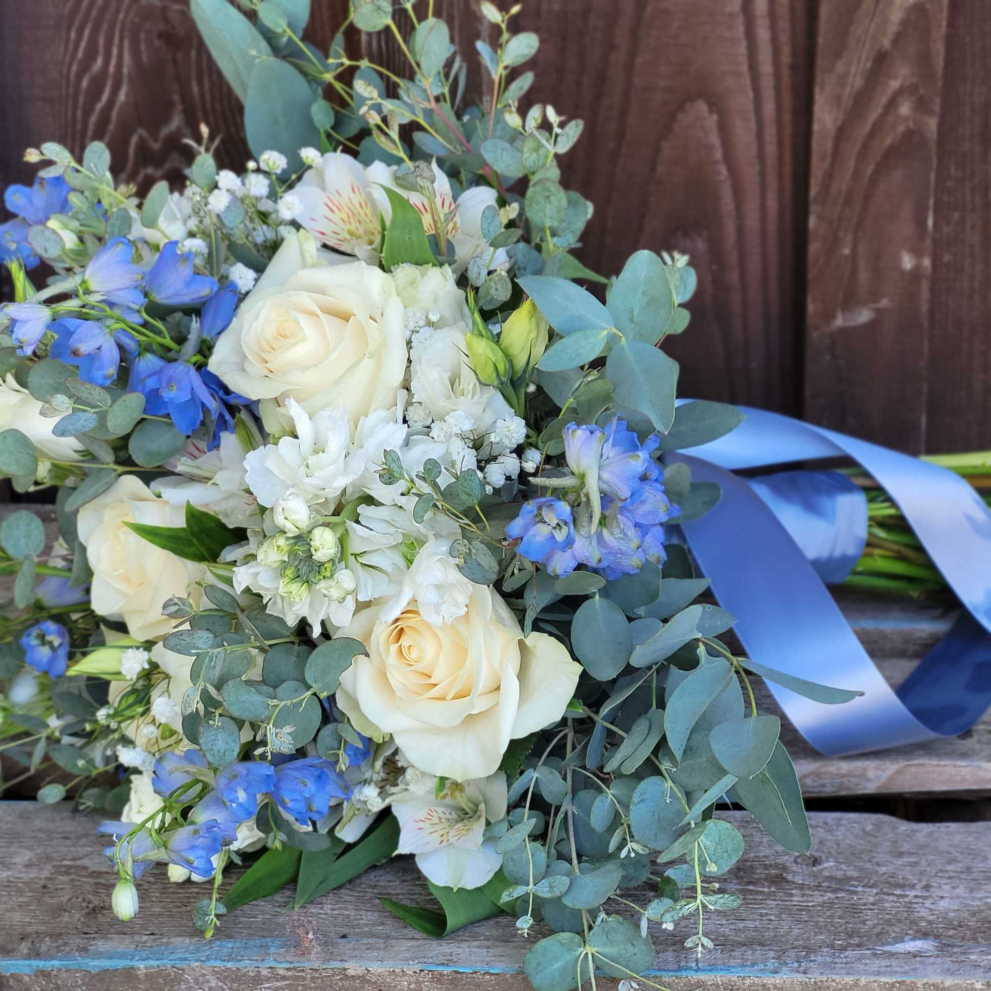 Bouquet of white roses and blue flowers tied with a blue ribbon