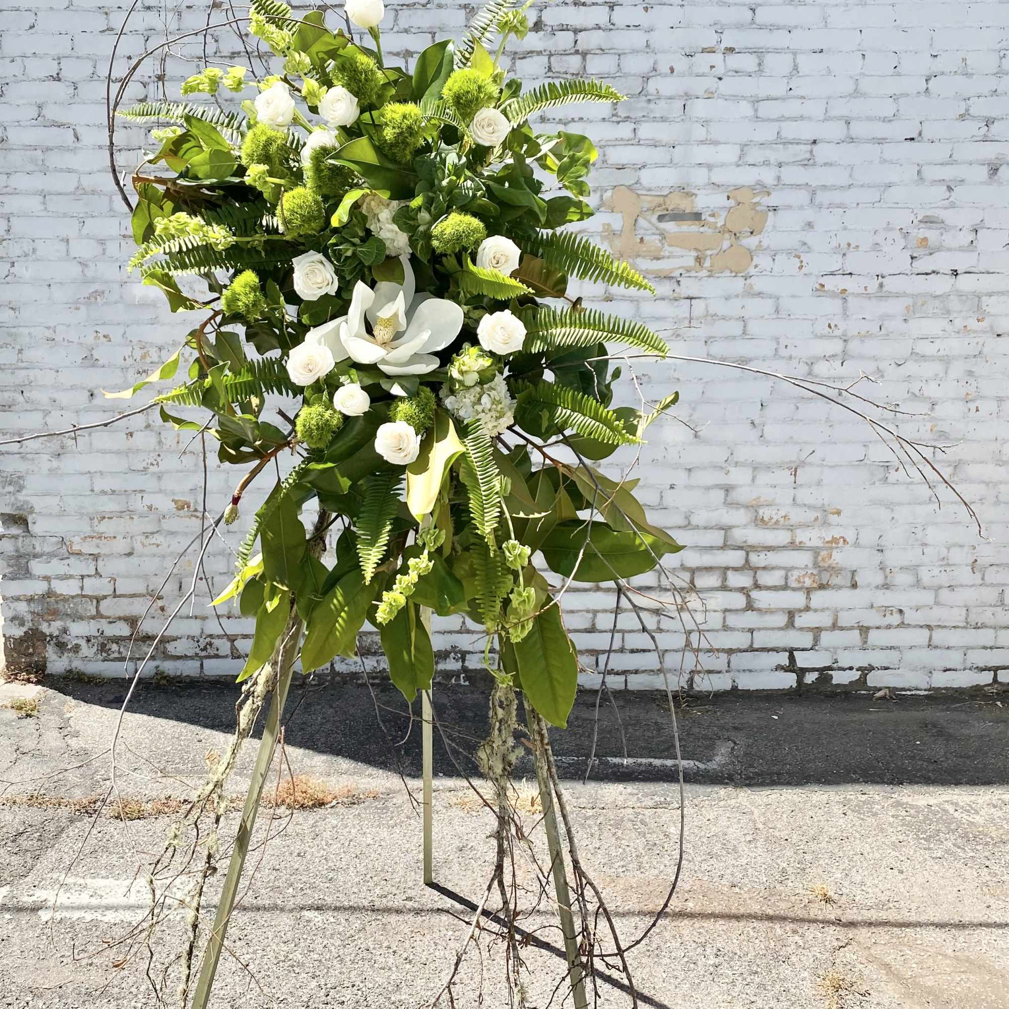 Tall white and green floral standing arrangement on a tripod easel