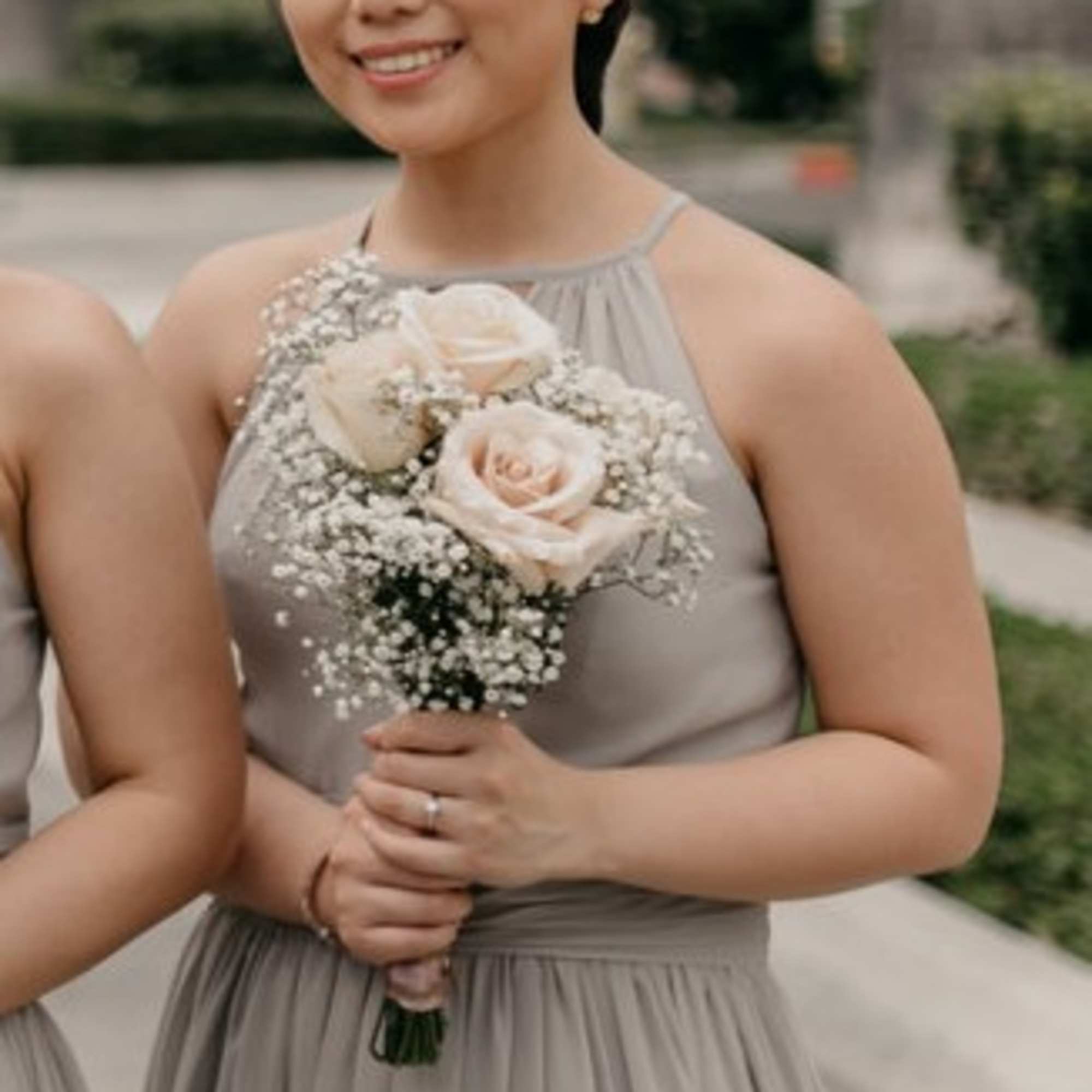 Bridesmaid holding a small bouquet of pale roses and baby's breath