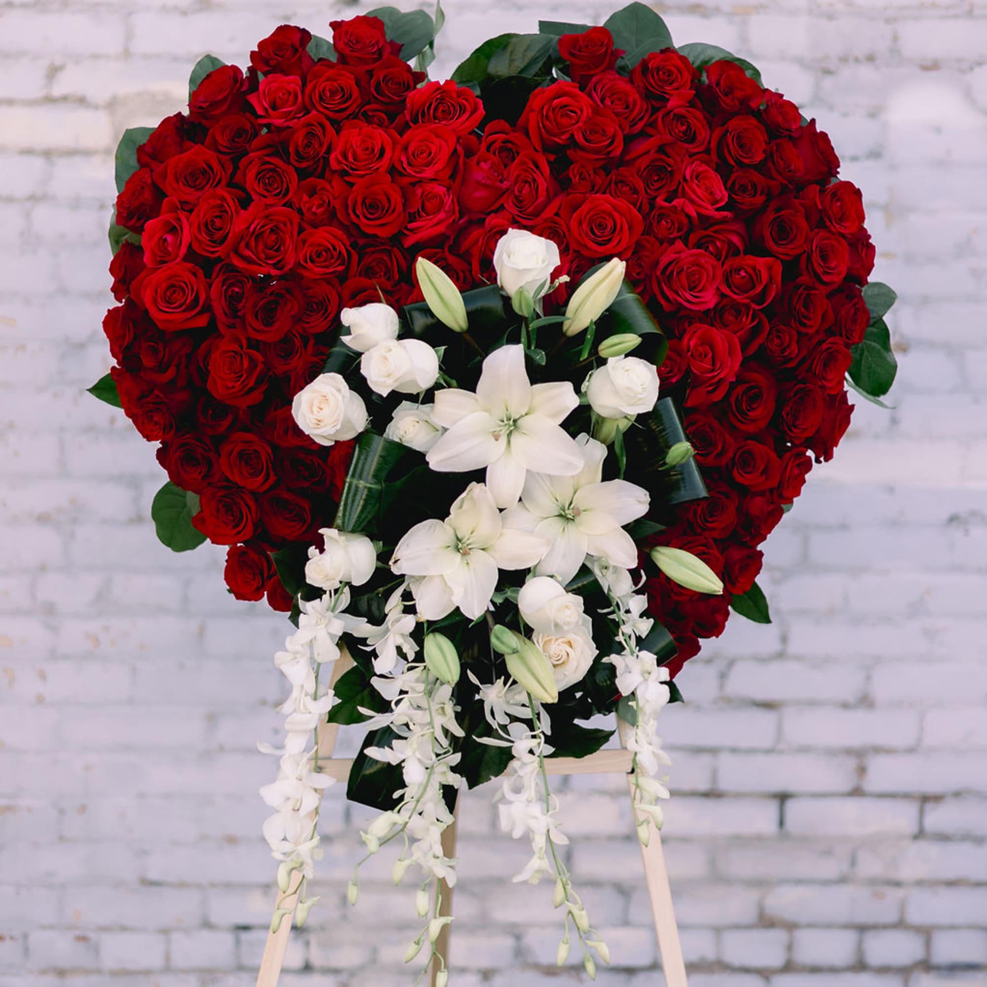 Heart-shaped red rose standing spray with white lilies and orchids