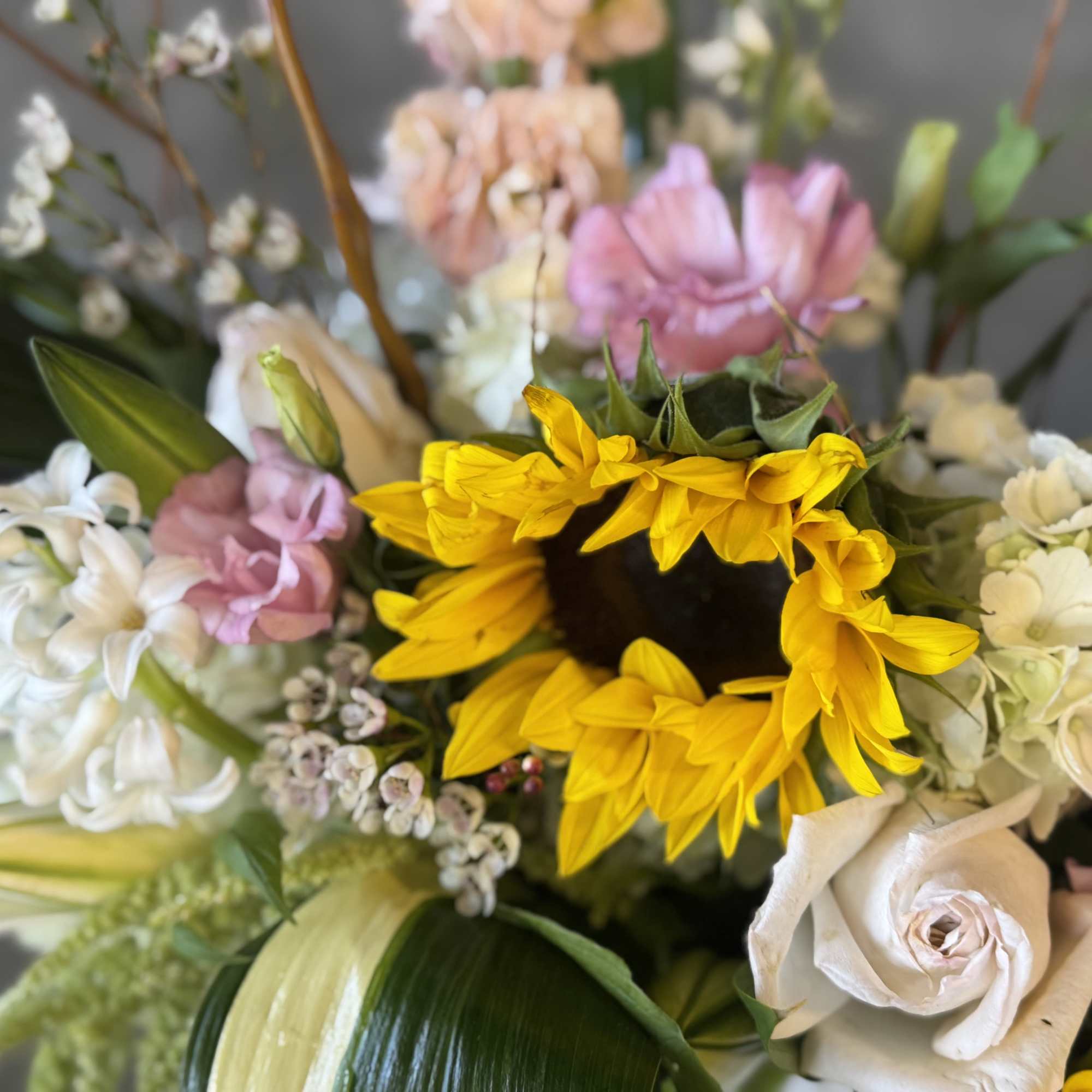 Bouquet with a bright yellow sunflower and pastel roses and lilies