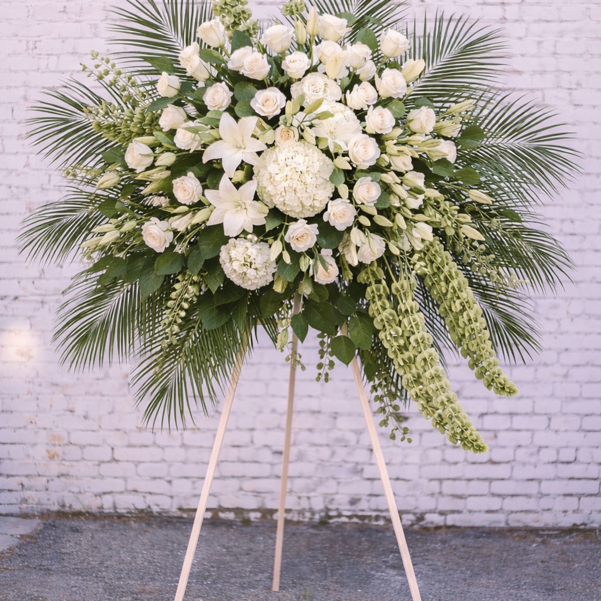 Large white floral standing spray on a wooden easel
