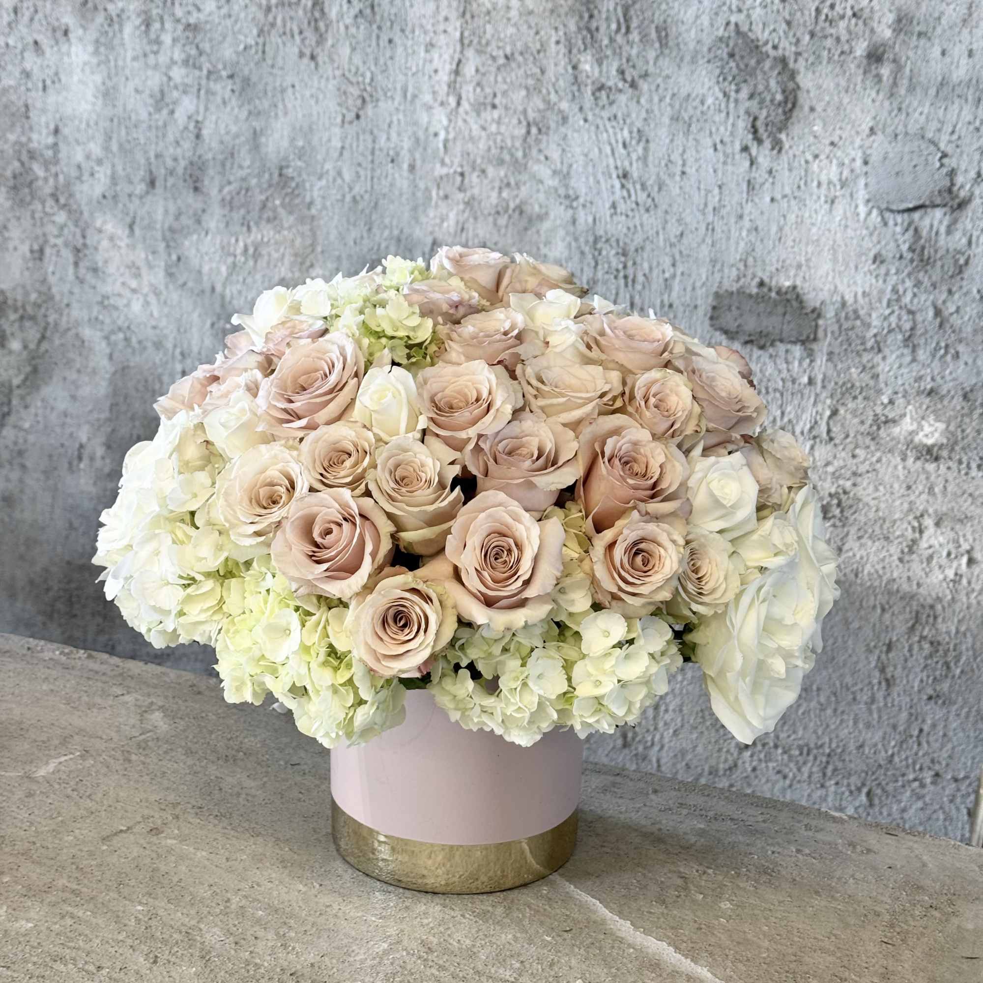 Blush roses and white hydrangeas in a pink round box