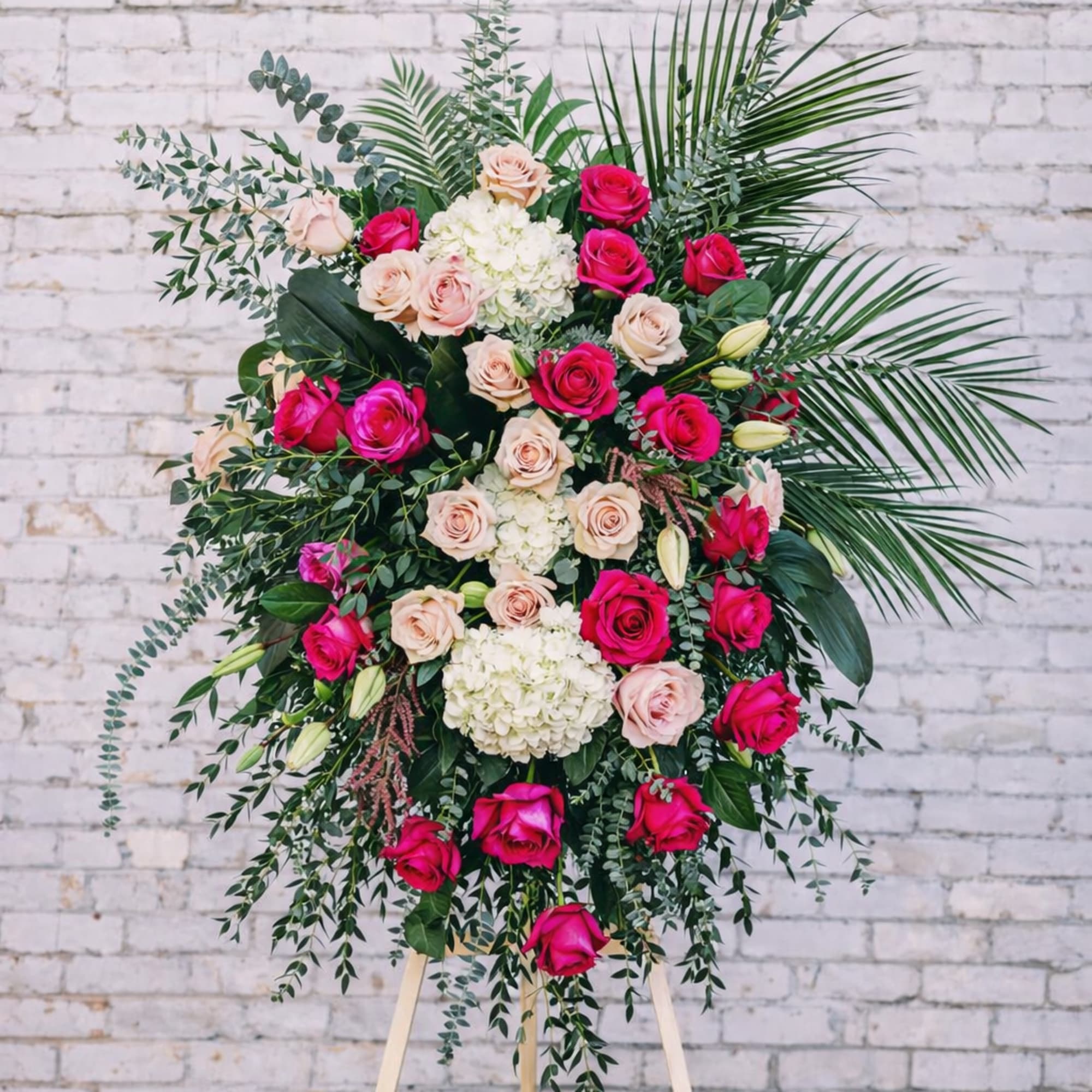 Large standing floral spray with pink and blush roses on an easel
