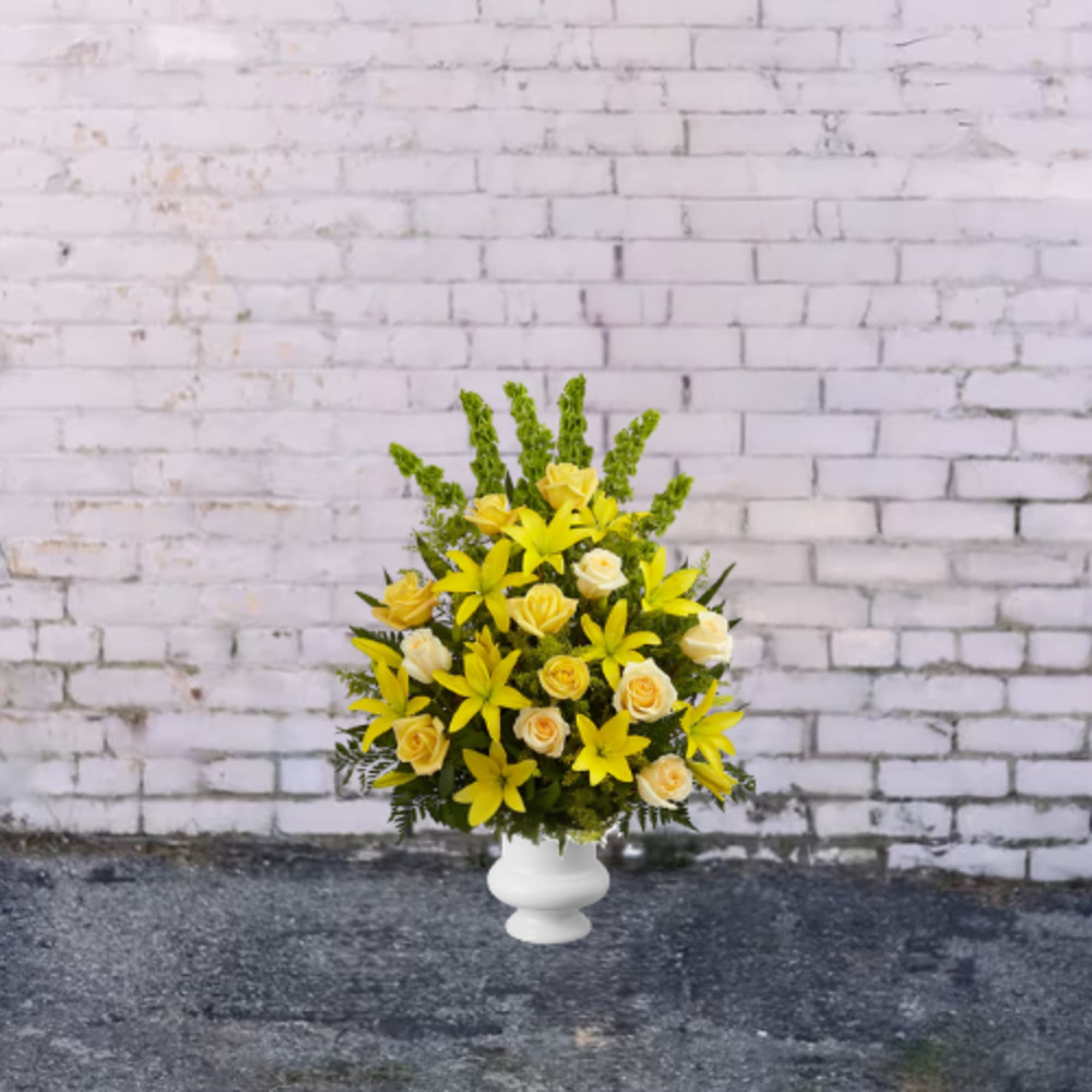 Yellow lilies and cream roses arranged in a white vase