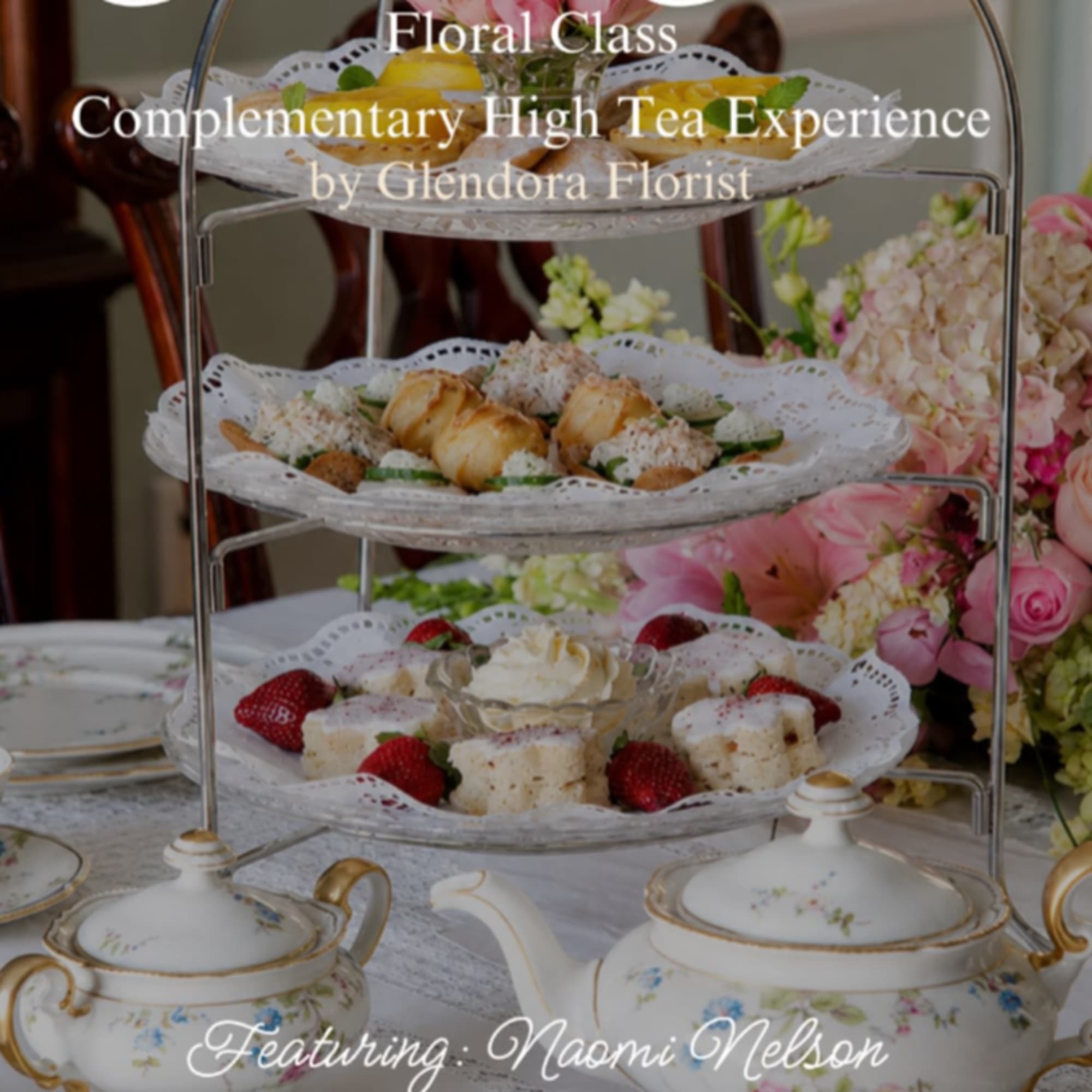 Tiered serving stand with pastries and flowers on a tea table