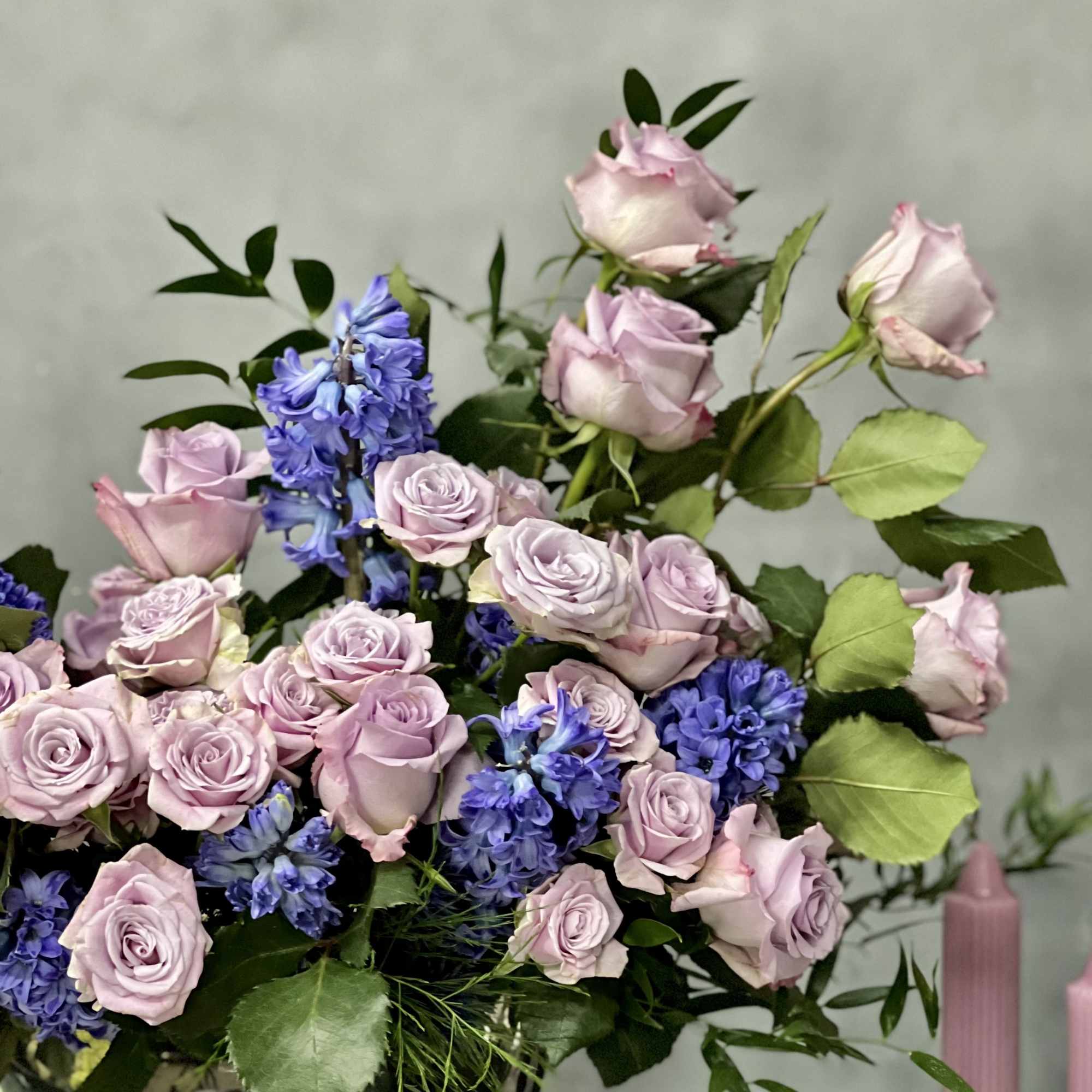 Arrangement of pale lavender roses and blue hyacinths against a gray background
