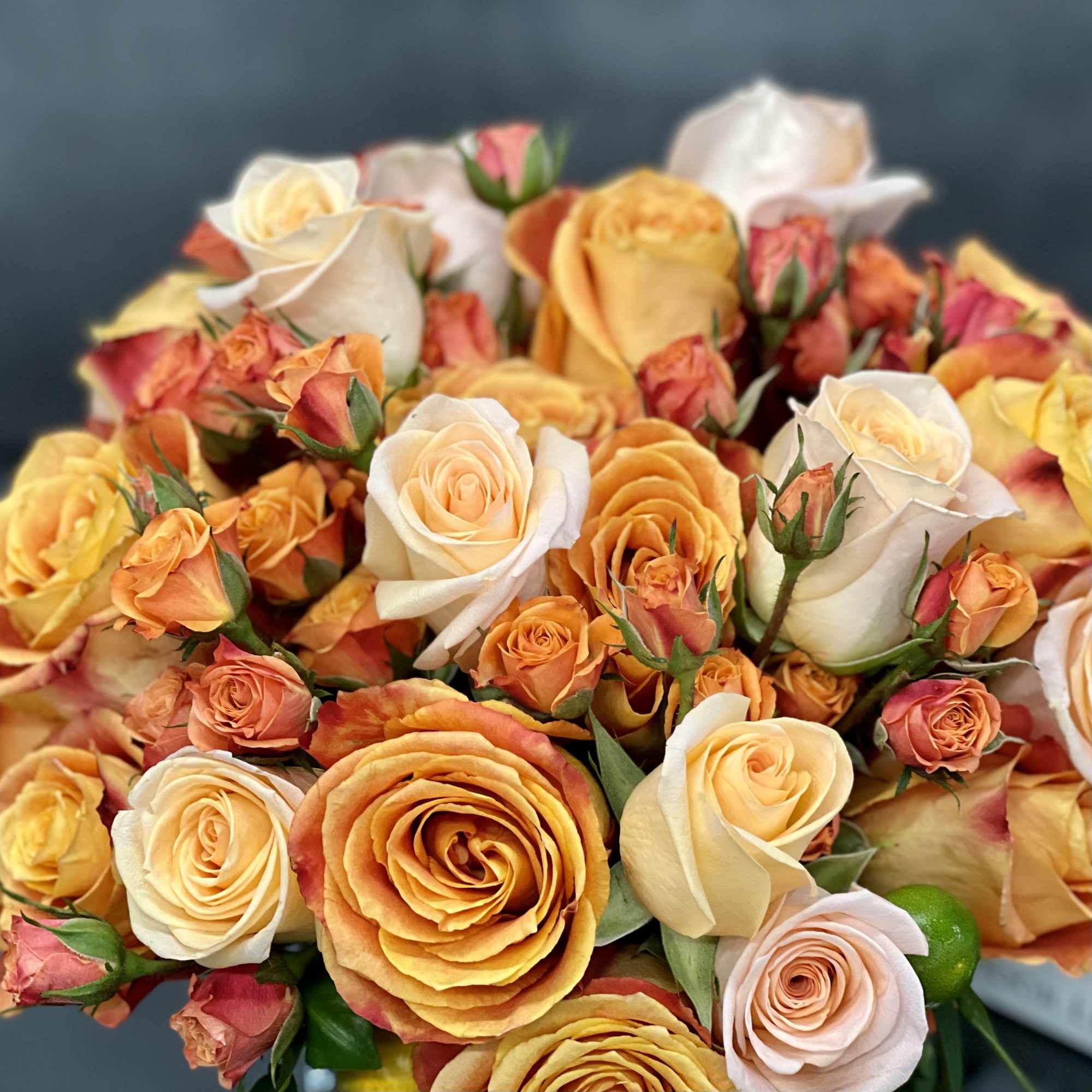 Tight bouquet of orange and cream roses and spray roses.