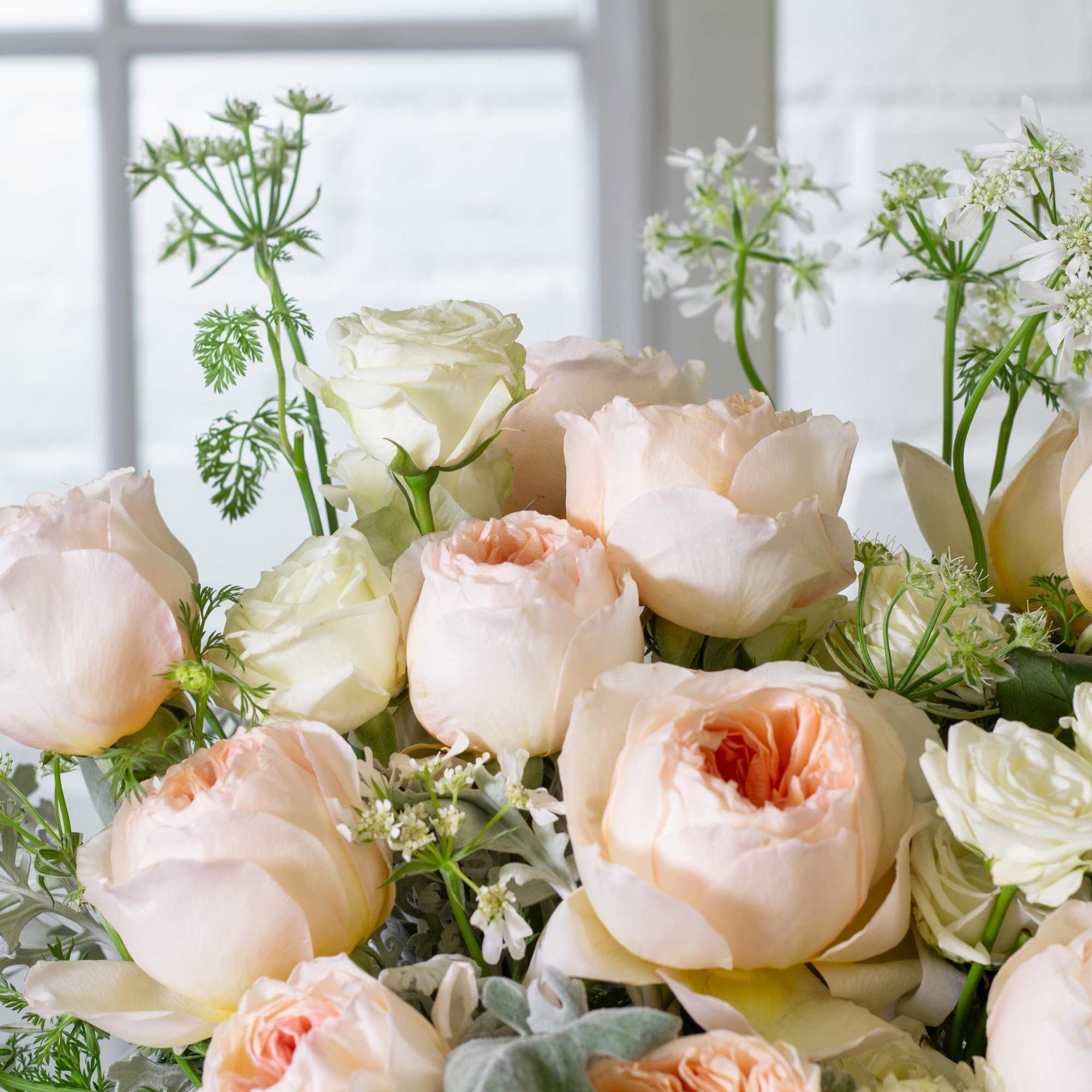Bouquet of pale peach and white roses with airy white filler flowers