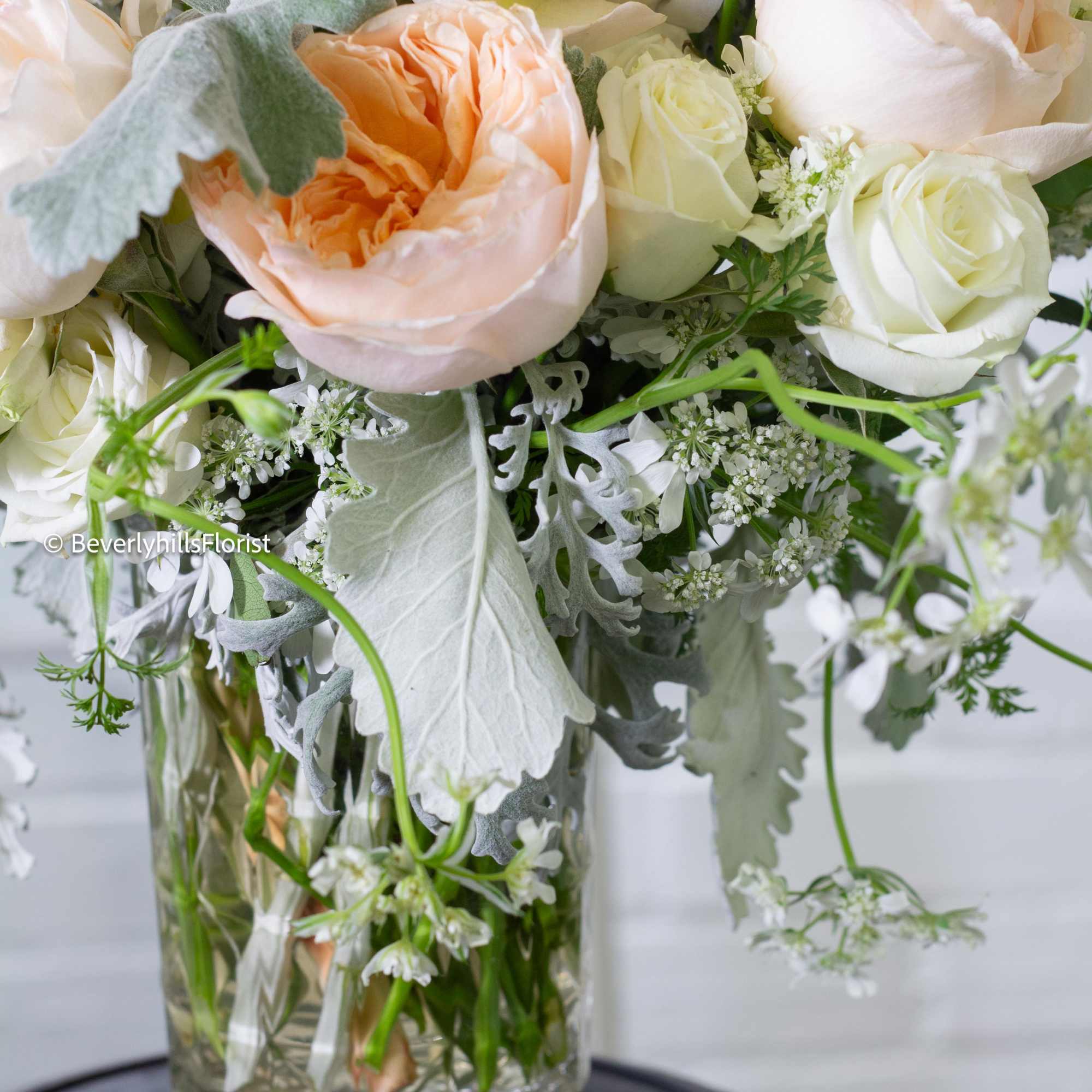 Peach and white roses arranged in a clear glass vase