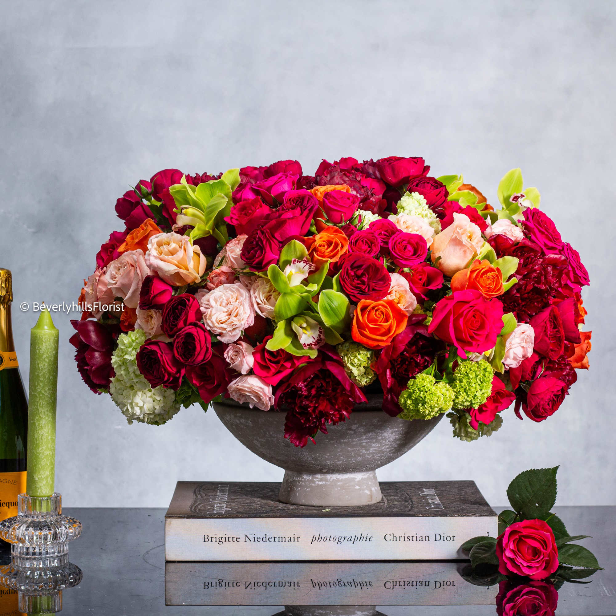 Large mixed bouquet of red, pink, and orange roses in a gray bowl vase