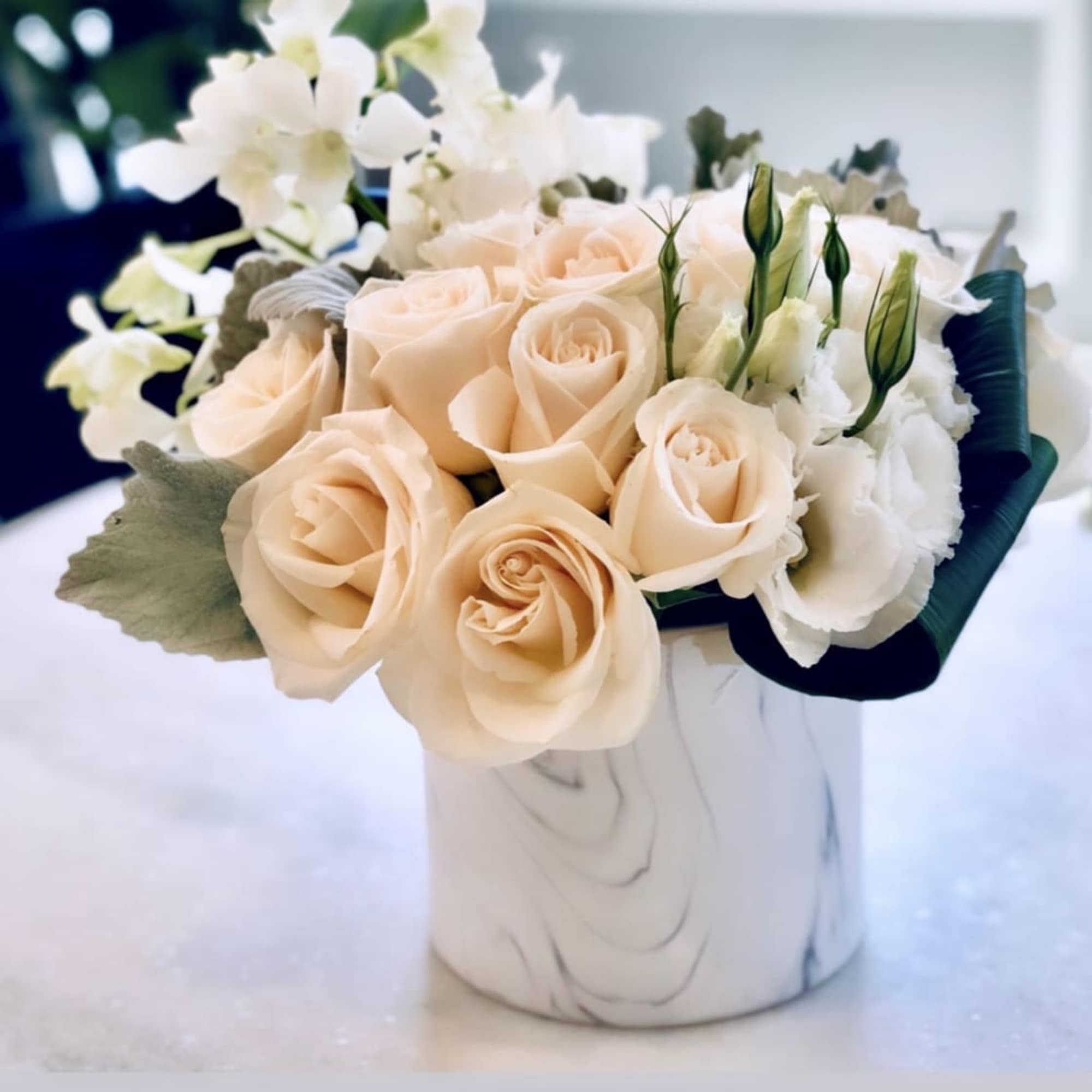 Peach roses and white flowers arranged in a white vase