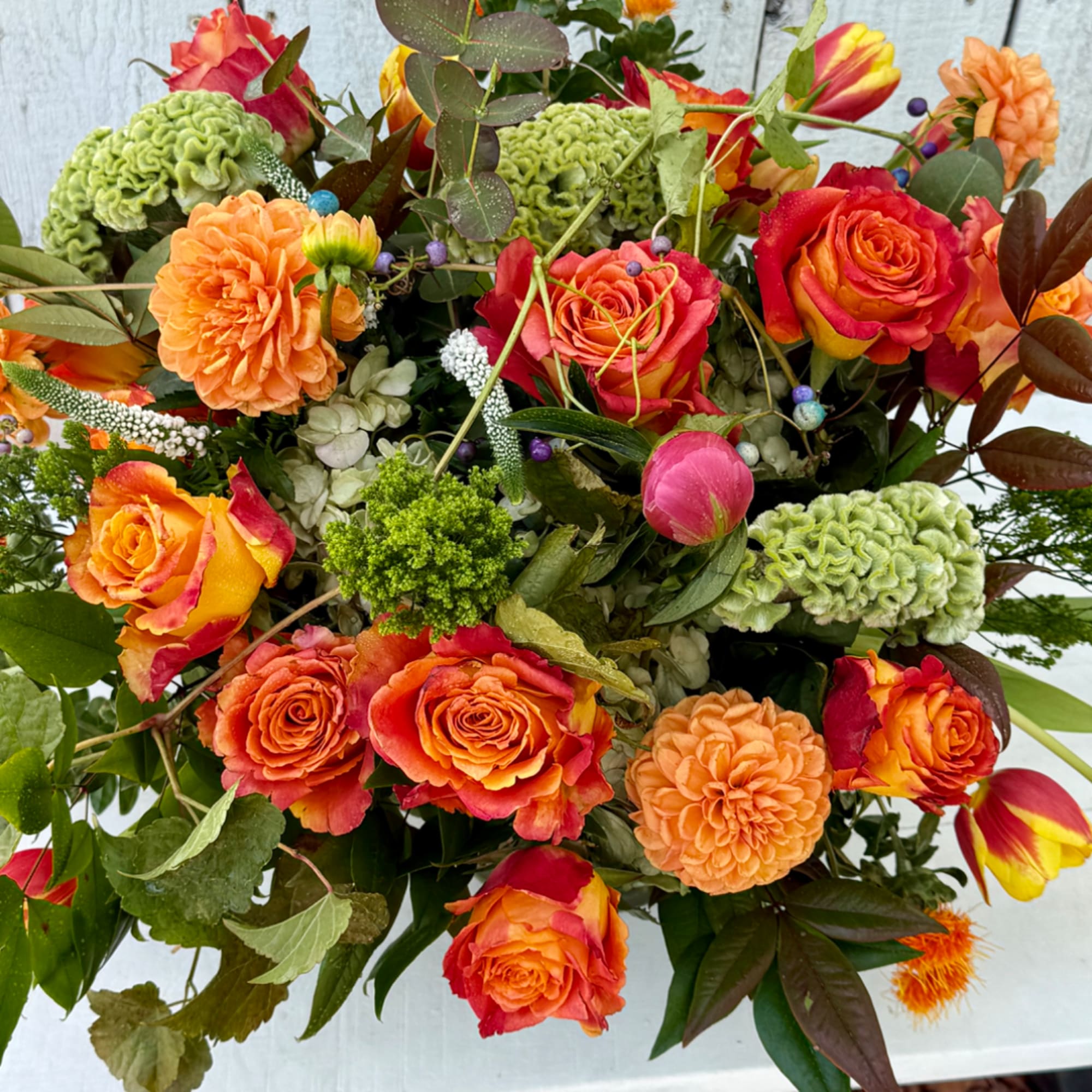 Bouquet of orange-red roses and orange dahlias with green accents