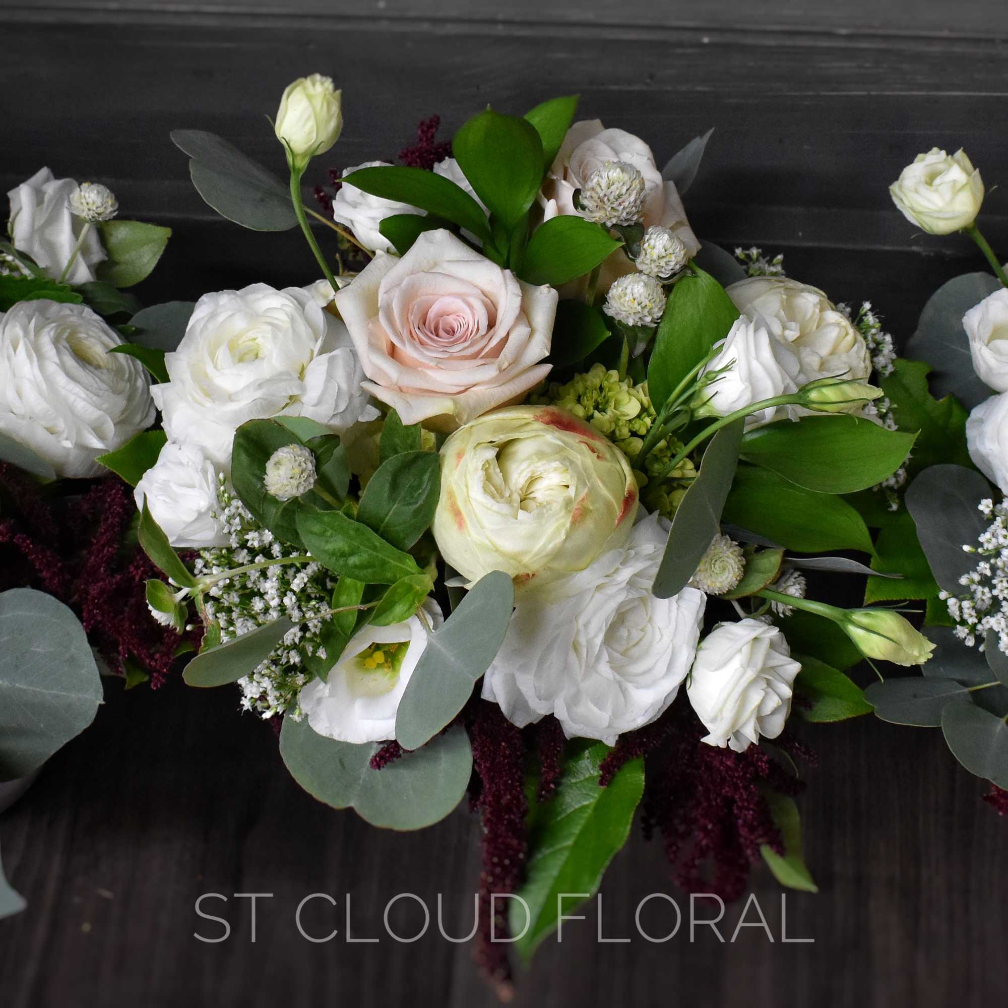 Three white and blush rose bouquets with greenery on a dark surface
